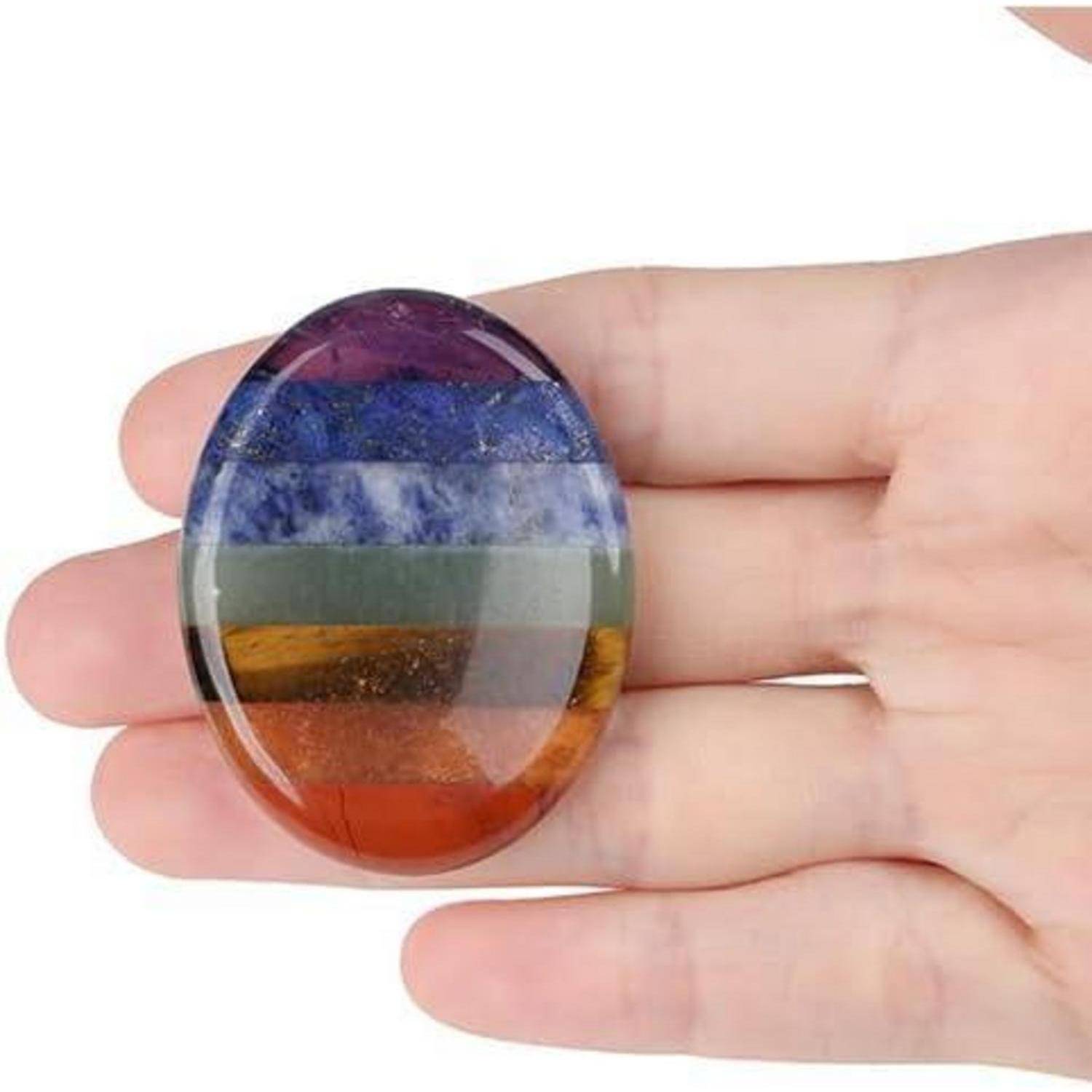 Eine Hand hält einen polierten Stein mit geschichteten Farben: Violett, Blau, Grün und Schattierungen von Bernstein, die verschiedene Energieebenen oder Chakren repräsentieren.