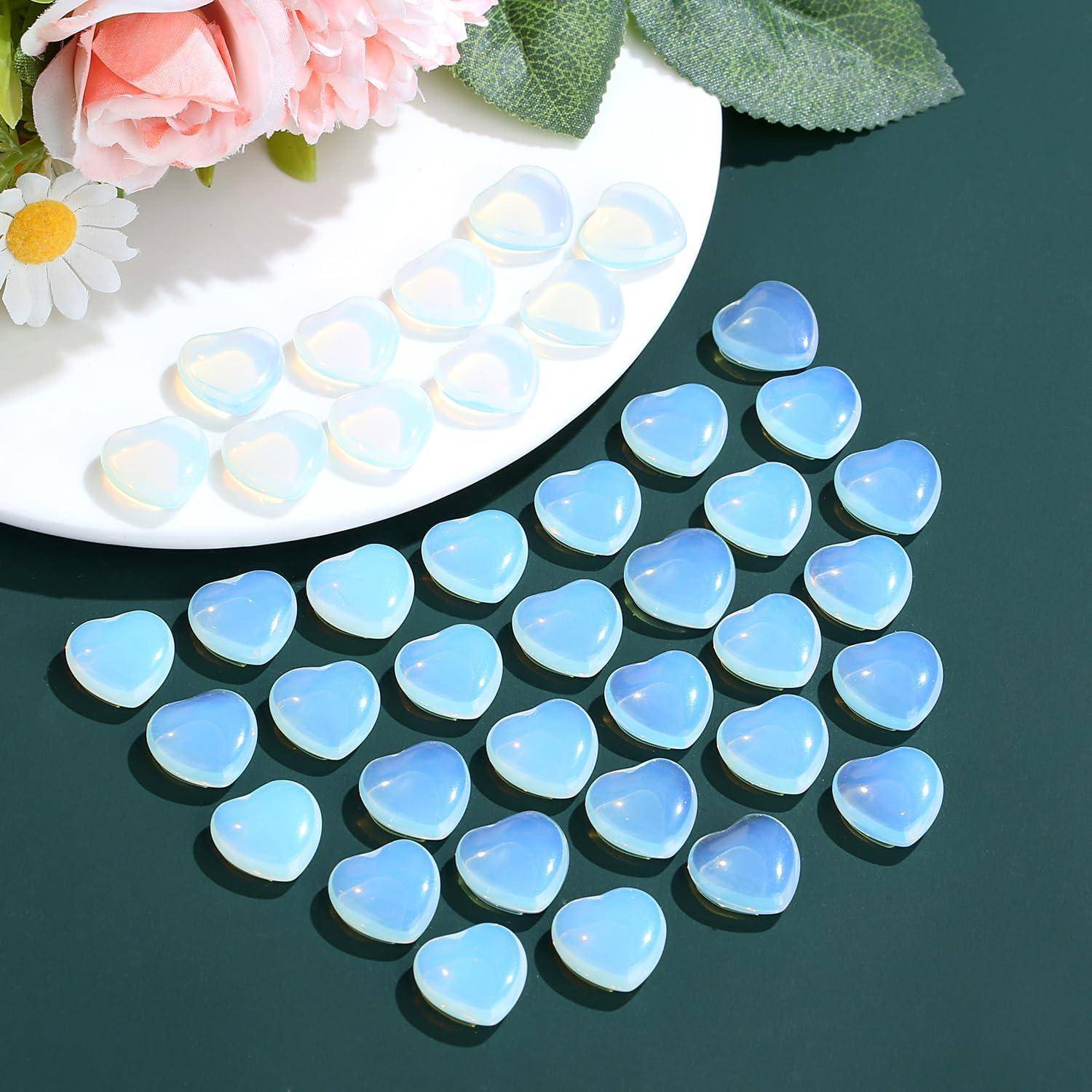 „Herzförmige blaue und weiße Perlen auf einer grünen Oberfläche neben rosa Rosen und weißen Gänseblümchen.
