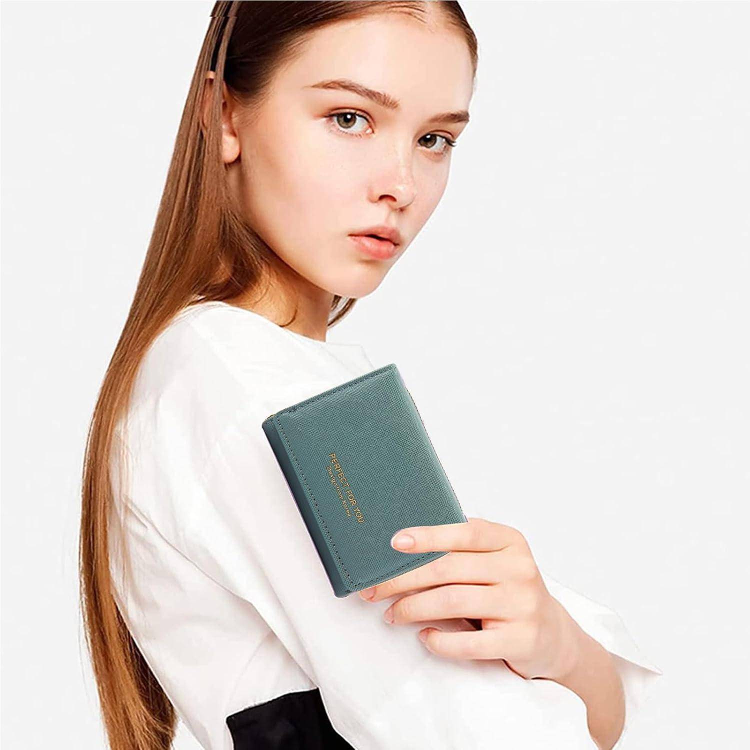 Eine junge Person mit langen Haaren hält vor einem schlichten weißen Hintergrund ein grünes Buch mit dem Titel 