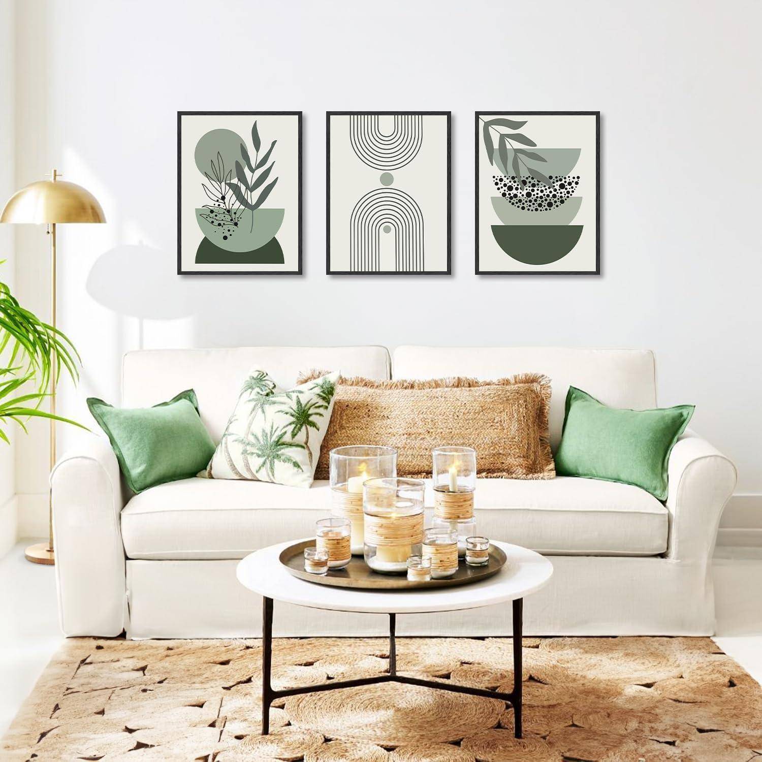 Ein stilvolles Wohnzimmer mit einem weißen Sofa, grünen und beigen Kissen, einem runden Couchtisch und drei abstrakten Kunstwerken an der Wand.