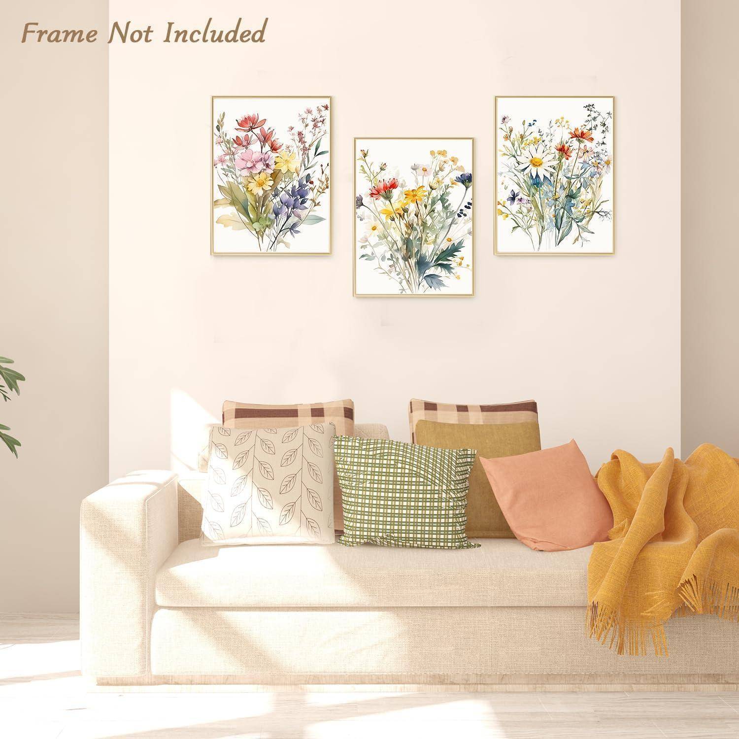 Wohnzimmerszene mit einem weißen Sofa, bunten Kissen und drei Blumengemälden an der Wand. Sanftes Licht schafft eine gemütliche Atmosphäre.