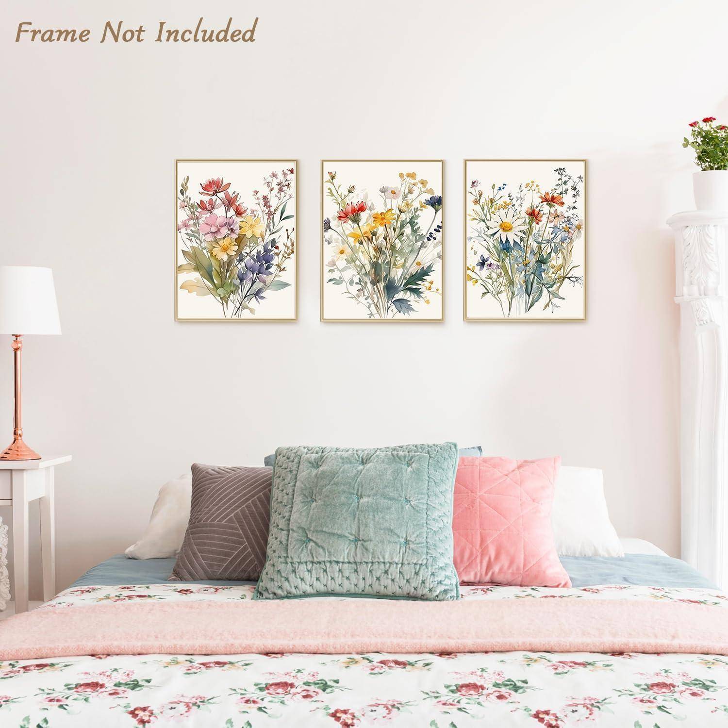 Ein Schlafzimmer zeigt ein ordentlich gemachtes Bett mit pastellfarbenen Kissen und Bettwäsche mit Blumenmuster. Über dem Bett sind drei florale Kunstwerke ausgestellt. Der Text 'Rahmen nicht enthalten' befindet sich oben links.