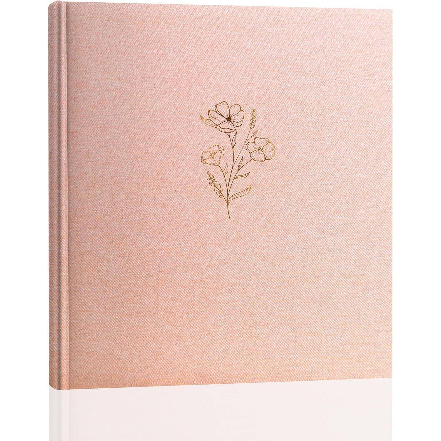 Ein rosa gebundenes Buch mit einer schlichten goldenen Blumenillustration auf dem Buchumschlag.