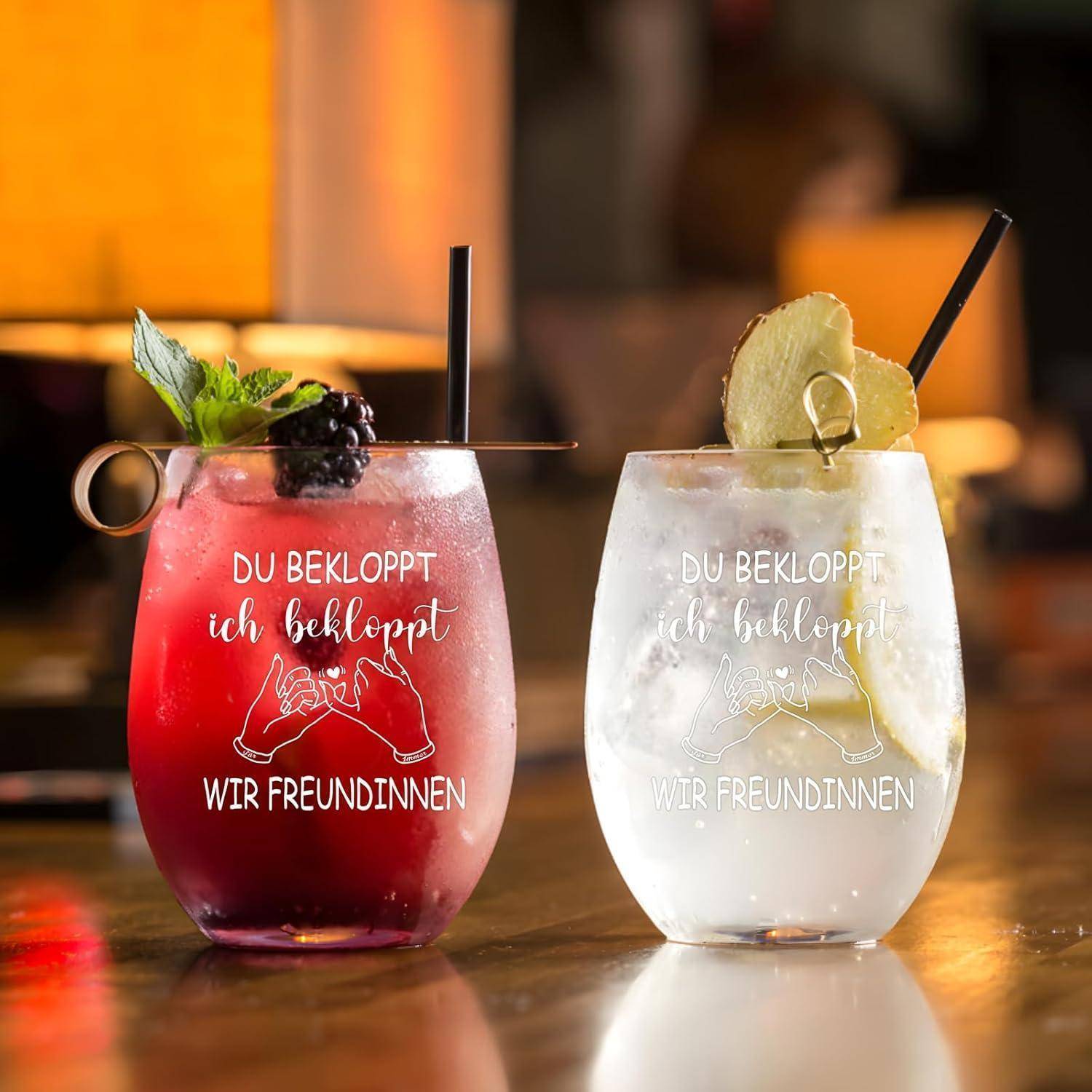 Zwei Cocktails mit Strohhalmen; links mit Brombeere und Minze als Garnitur, rechts mit Limette. Gläser mit Aufschrift: 