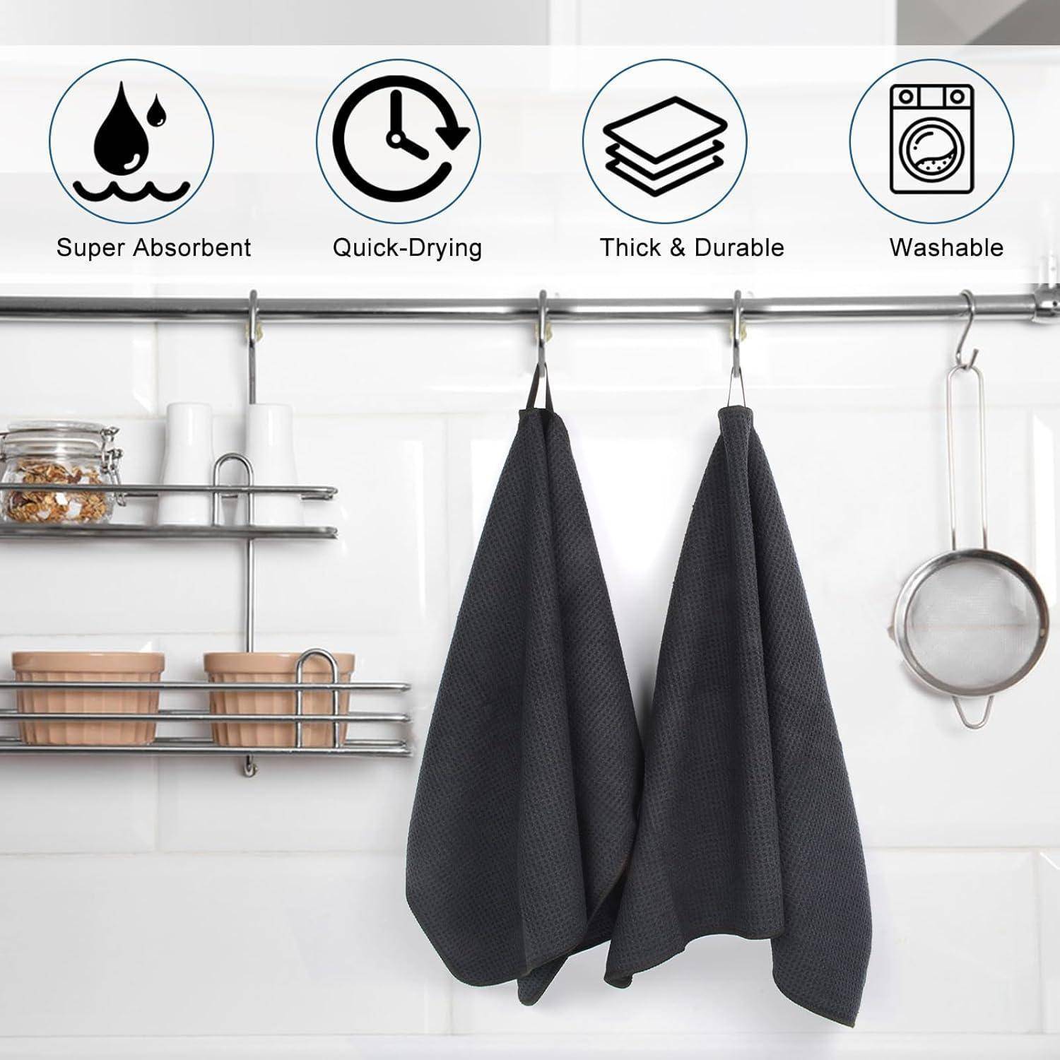Zwei dunkle Handtücher hängen an einer Küchenleiste mit Ablageregalen. Über den Handtüchern zeigen Icons Merkmale hervor: „Super absorptionsfähig