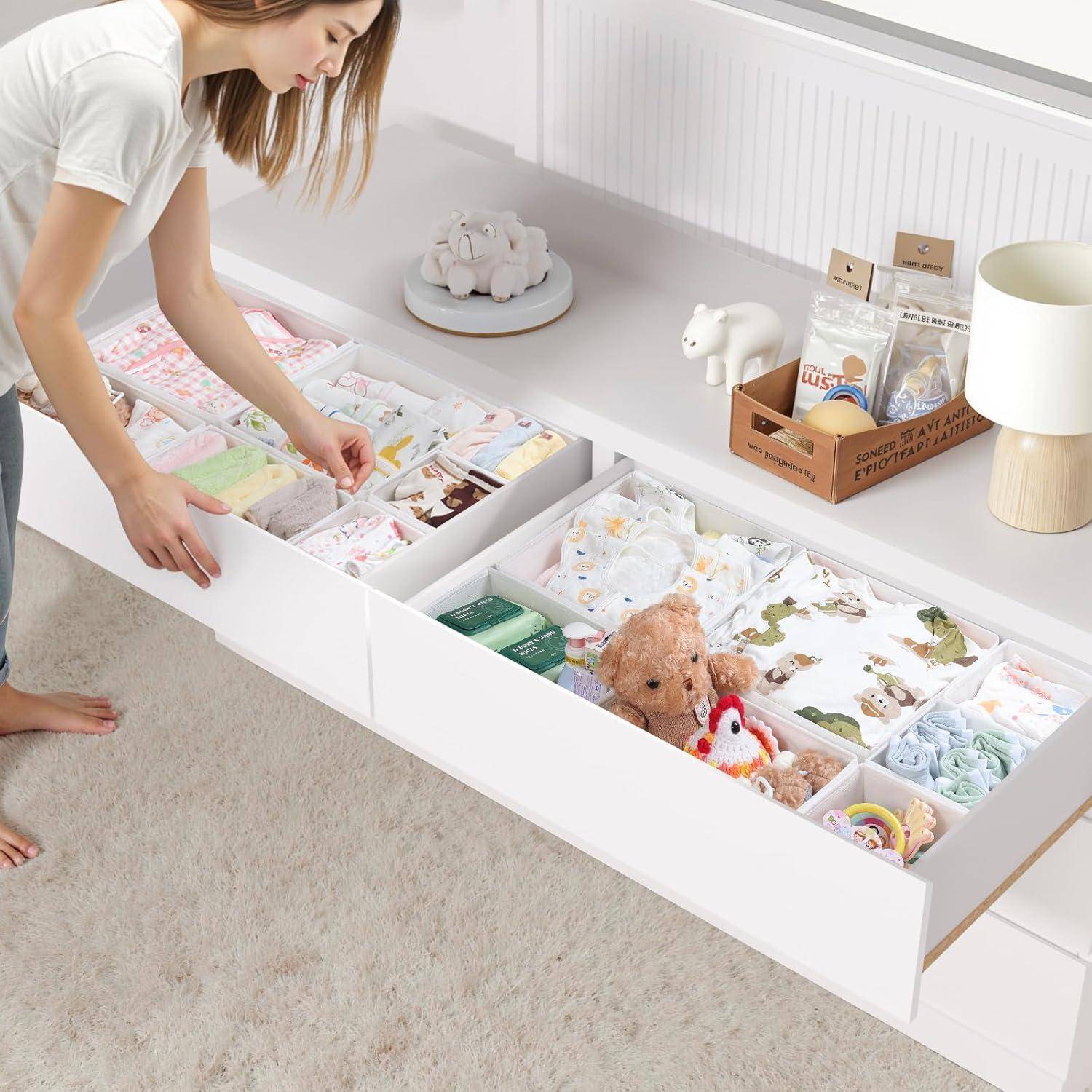 Eine Person ordnet Gegenstände in offenen Schubladen an, darunter Babykleidung und Plüschtiere. Die Szene vermittelt den Eindruck von Ordentlichkeit und häuslicher Organisation.