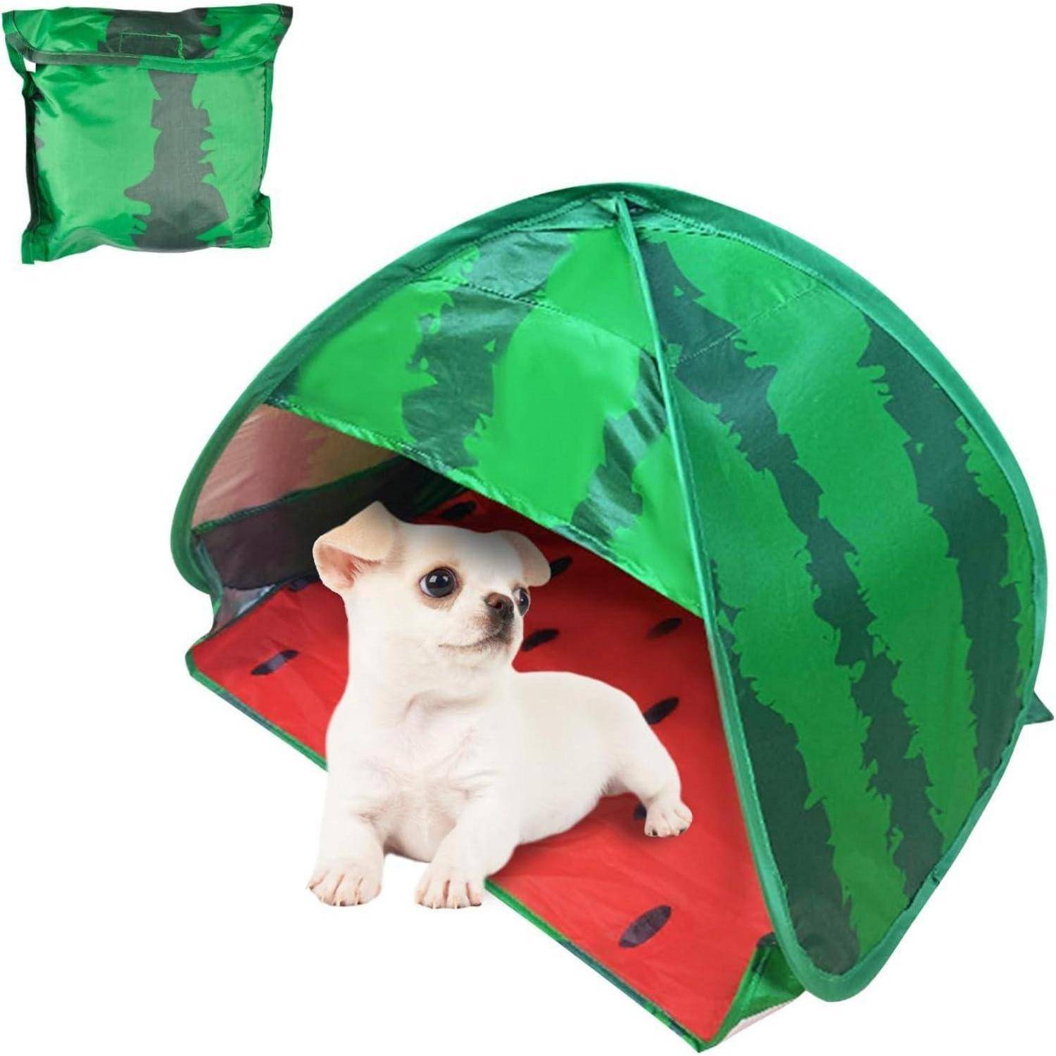 Ein kleiner weißer Hund liegt auf einer roten Matte unter einem grünen, wassermelonen-thematischen Haustierzelt. Das Zelt ist in einem kleinen Einsatzbild zusammengefaltet dargestellt.