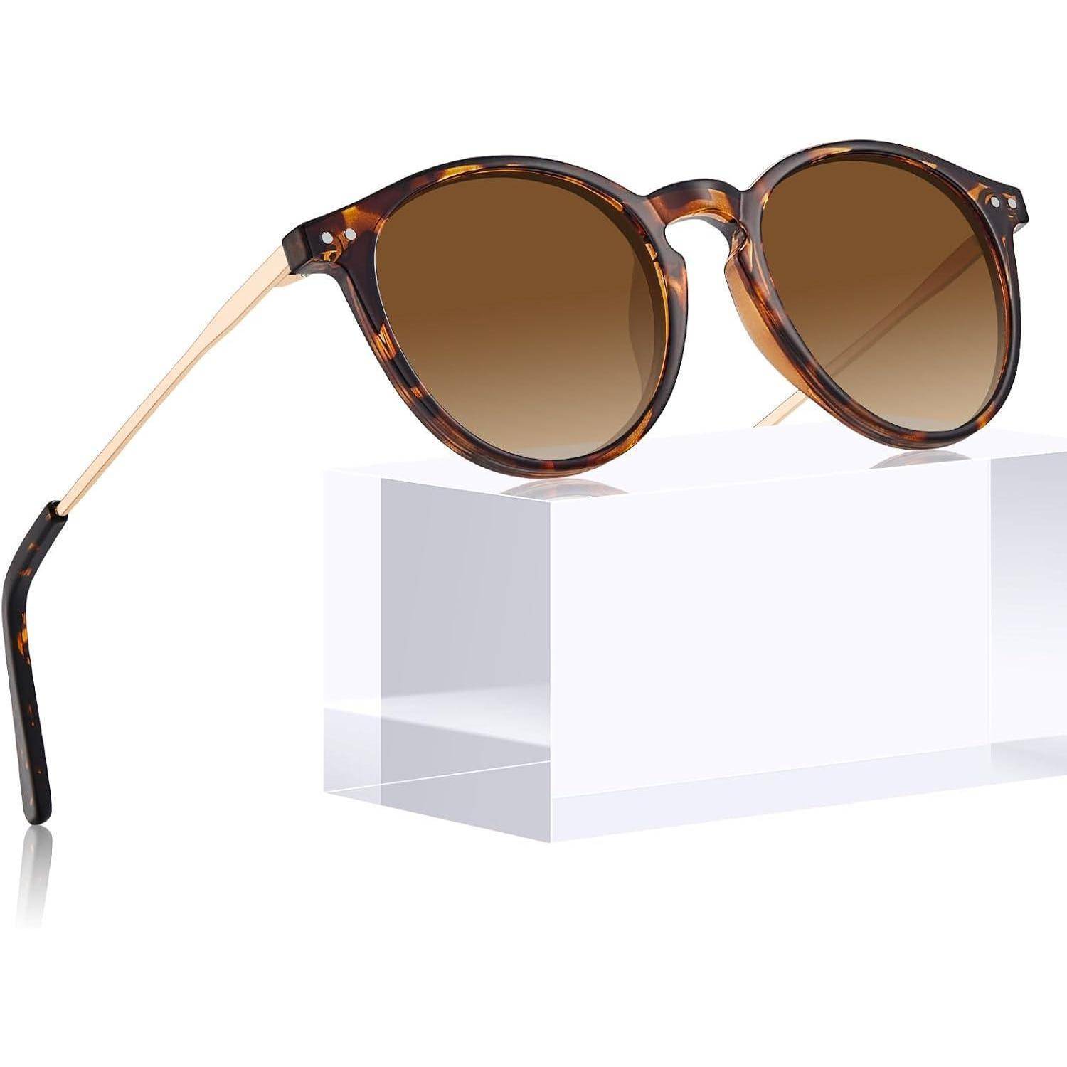 Schildpatt-Sonnenbrille in runder Form mit braunen Verlaufsgläsern, auf einem klaren Ständer präsentiert mit dünnen goldenen Bügeln.