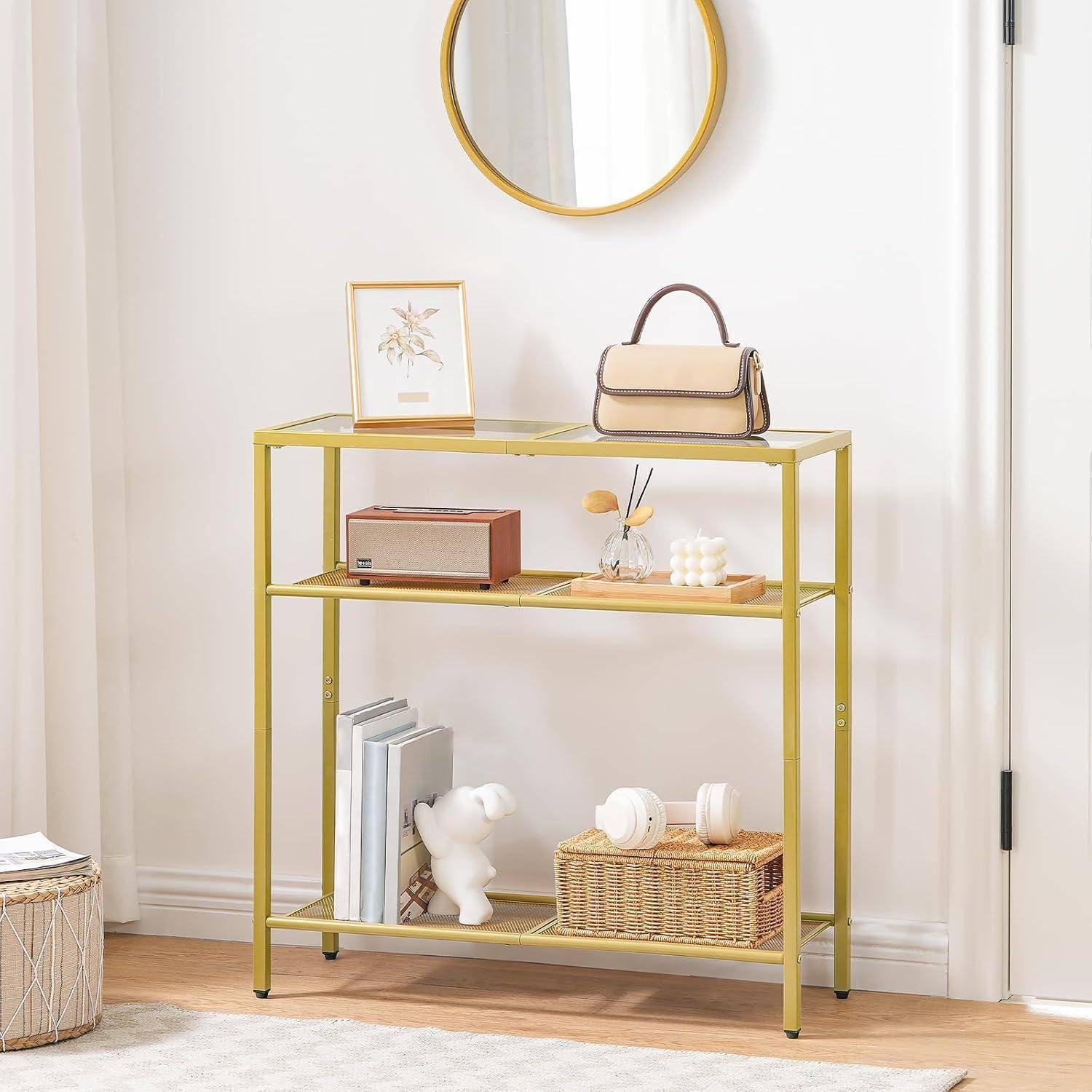 Ein kleiner, eleganter Konsolentisch mit einem goldenen Rahmen präsentiert einen runden Spiegel darüber. Er trägt eine Handtasche, ein gerahmtes Bild und dekorative Gegenstände.