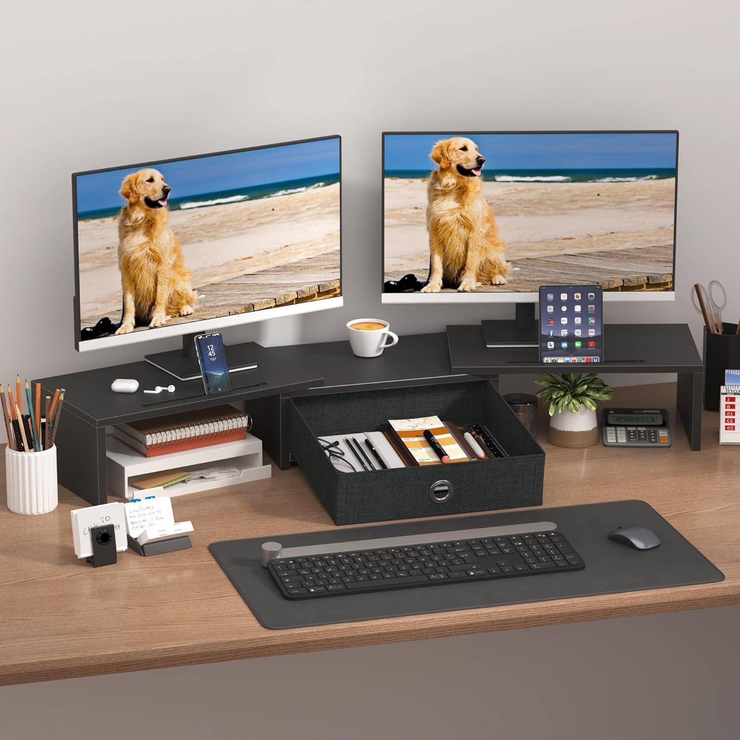 Ein aufgeräumter Schreibtisch mit zwei Monitoren, auf denen ein Golden Retriever am Strand zu sehen ist, dazu eine Tastatur, ein Telefonhalter, ein Taschenrechner und organisierte Aufbewahrungsmöglichkeiten.