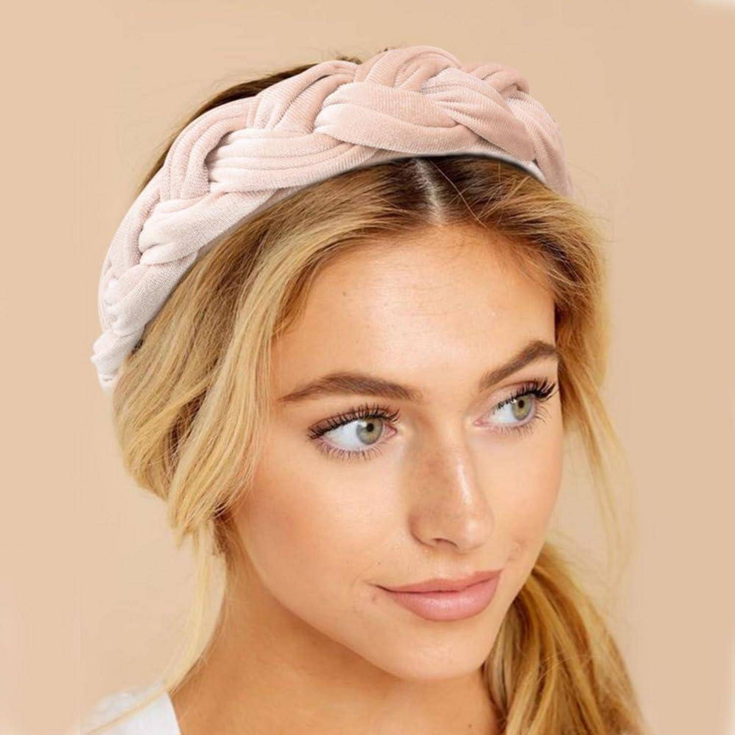 Eine Frau mit einem geflochtenen Haarband blickt leicht zur Seite. Der Hintergrund ist in einem weichen Beige gehalten.
