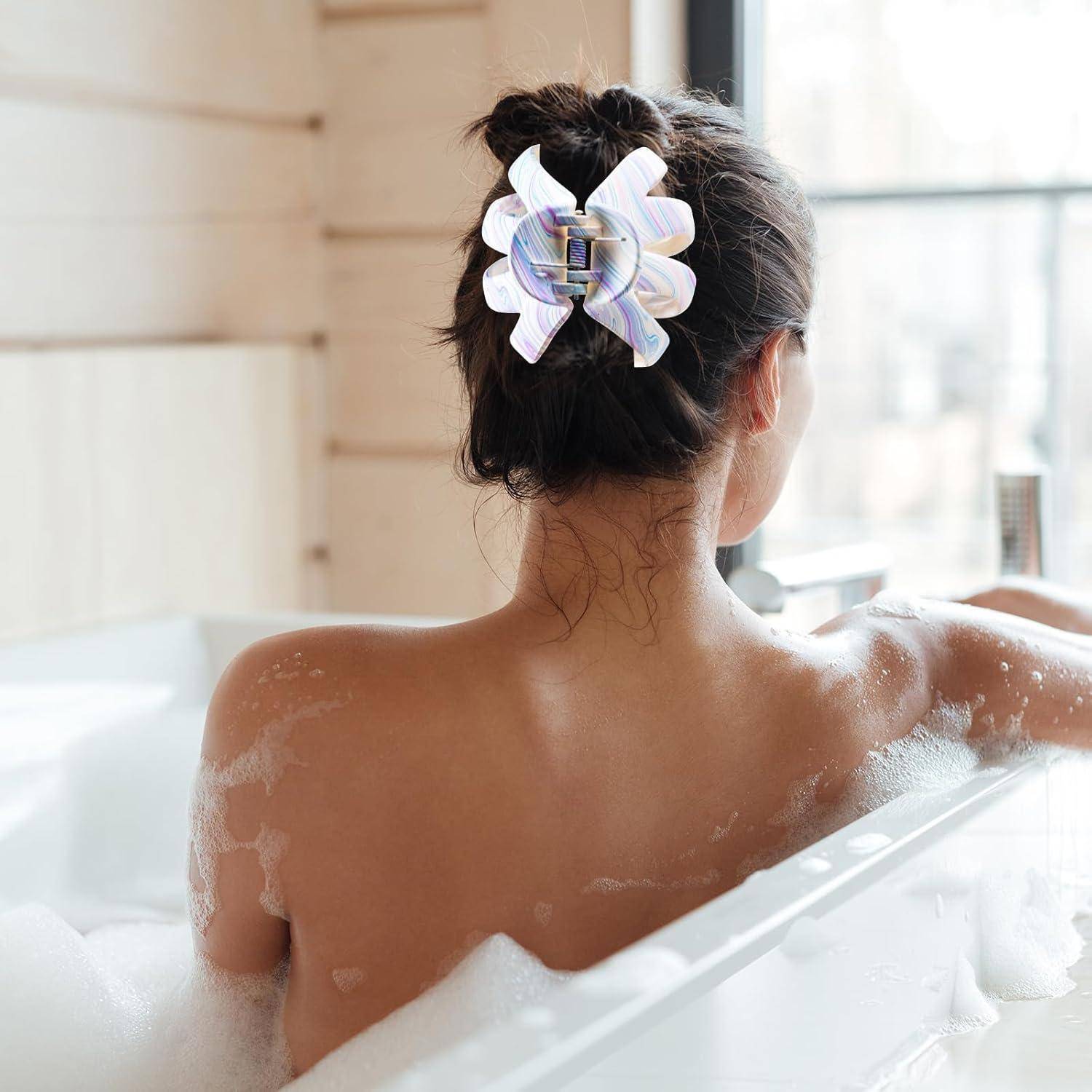 Eine Frau mit hochgestecktem Haar, das von einer dekorativen Klammer zusammengehalten wird, entspannt sich in einer mit Schaumblasen gefüllten Badewanne in der Nähe eines Fensters, durch das weiches Licht hereinströmt.