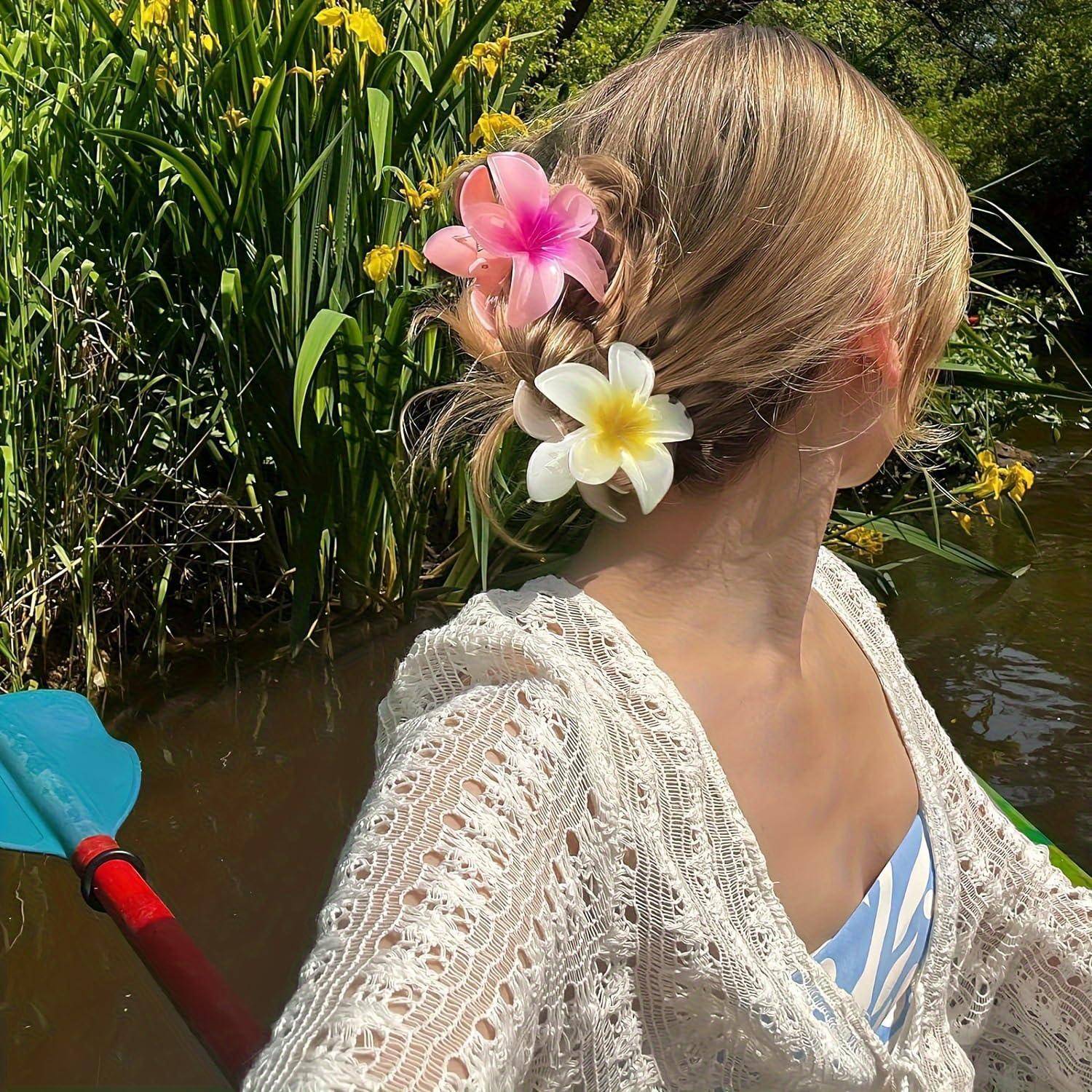 Eine Frau mit Blumen im Haar paddelt ein Kajak auf einem See, umgeben von Grün und gelben Blumen, unter einem klaren Himmel.