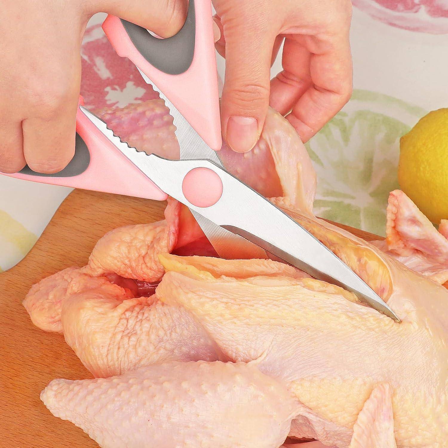 Zwei Hände schneiden rohes Hähnchen mit Küchenscheren auf einem Holzbrett; teilweise ist eine Zitrone daneben zu sehen.