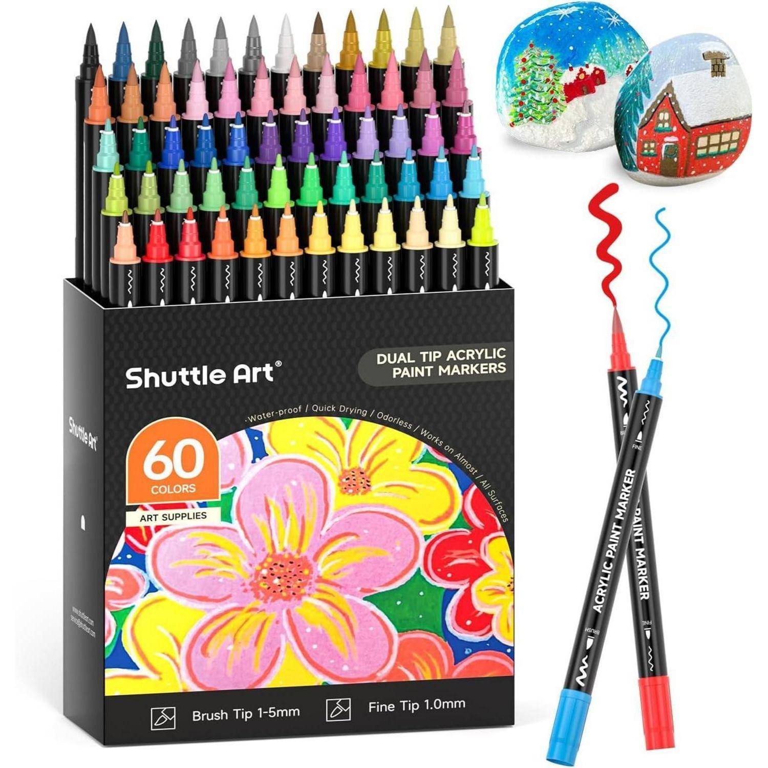 Ein Set von 60 Shuttle Art Dual-Spitzen Acrylfarb-Markern, präsentiert mit bunten Kappen. Zwei bemalte Steine mit Designs sind neben der Box zu sehen.