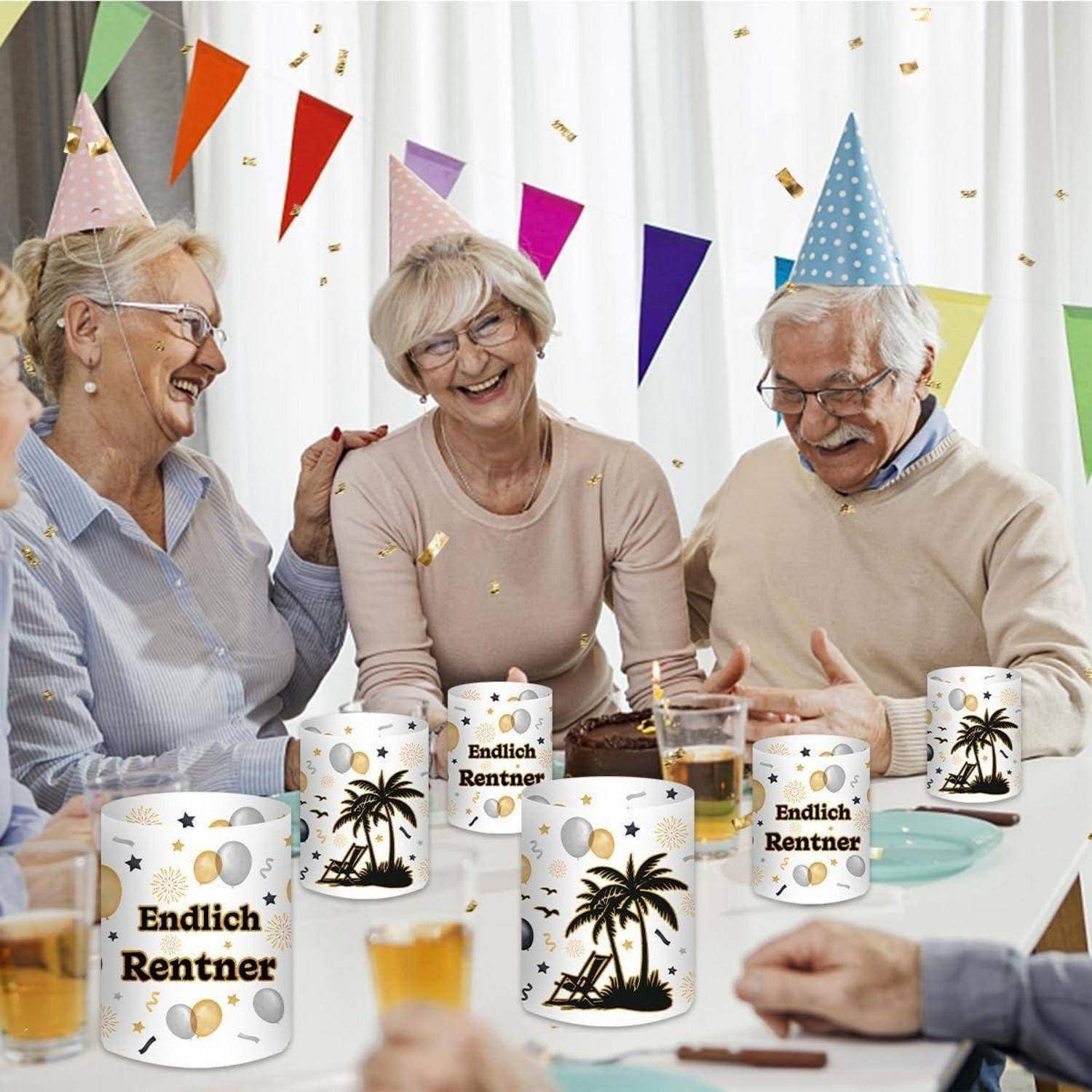 Eine Gruppe älterer Menschen feiert mit Partyhüten und Getränken, lächelt und lacht. Mehrere Tassen tragen die Aufschrift ‚Endlich Rentner'.