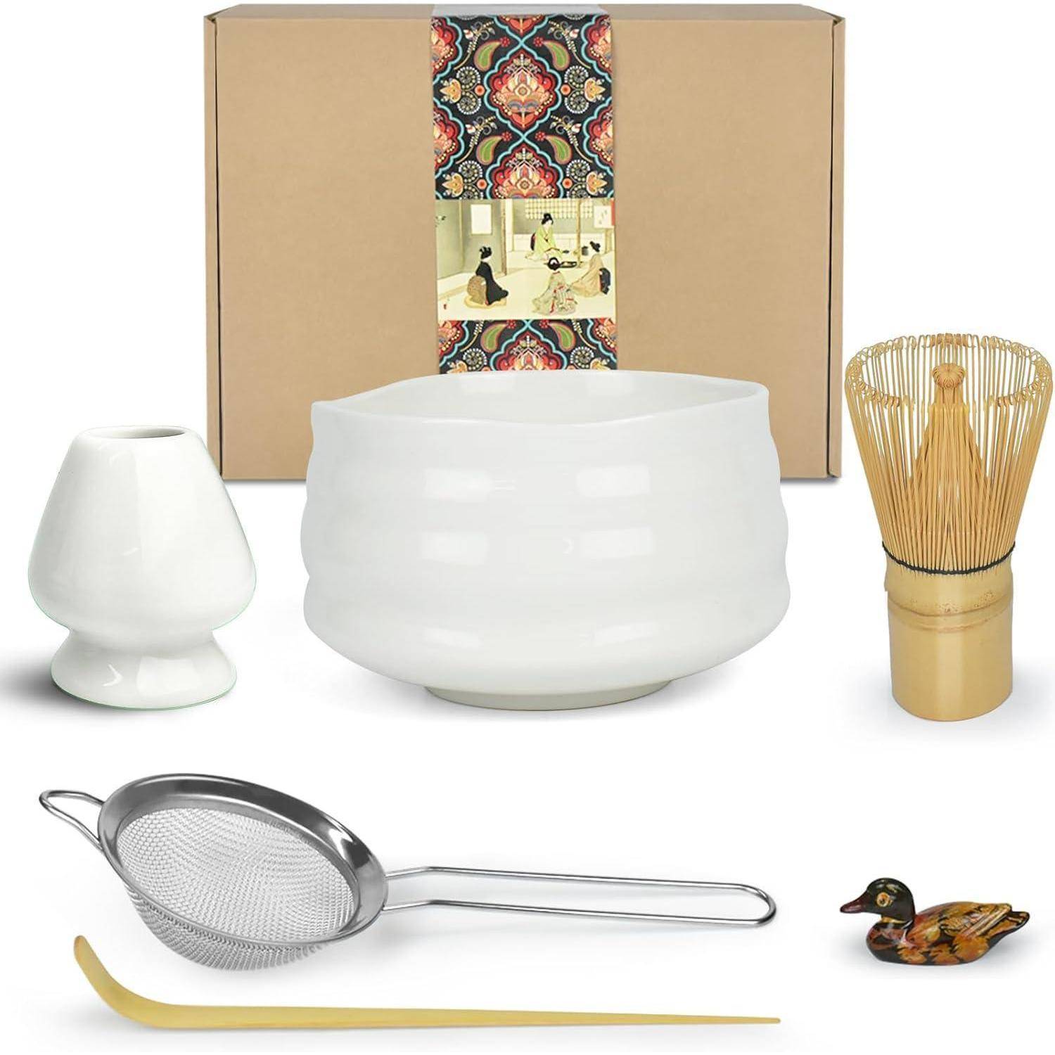 Ein japanisches Teezeremonie-Set, bestehend aus einer weißen Schale, einem Schneebesen, einem Sieb, einem Löffel und einer Entenfigur, präsentiert mit dekorativer Verpackung.