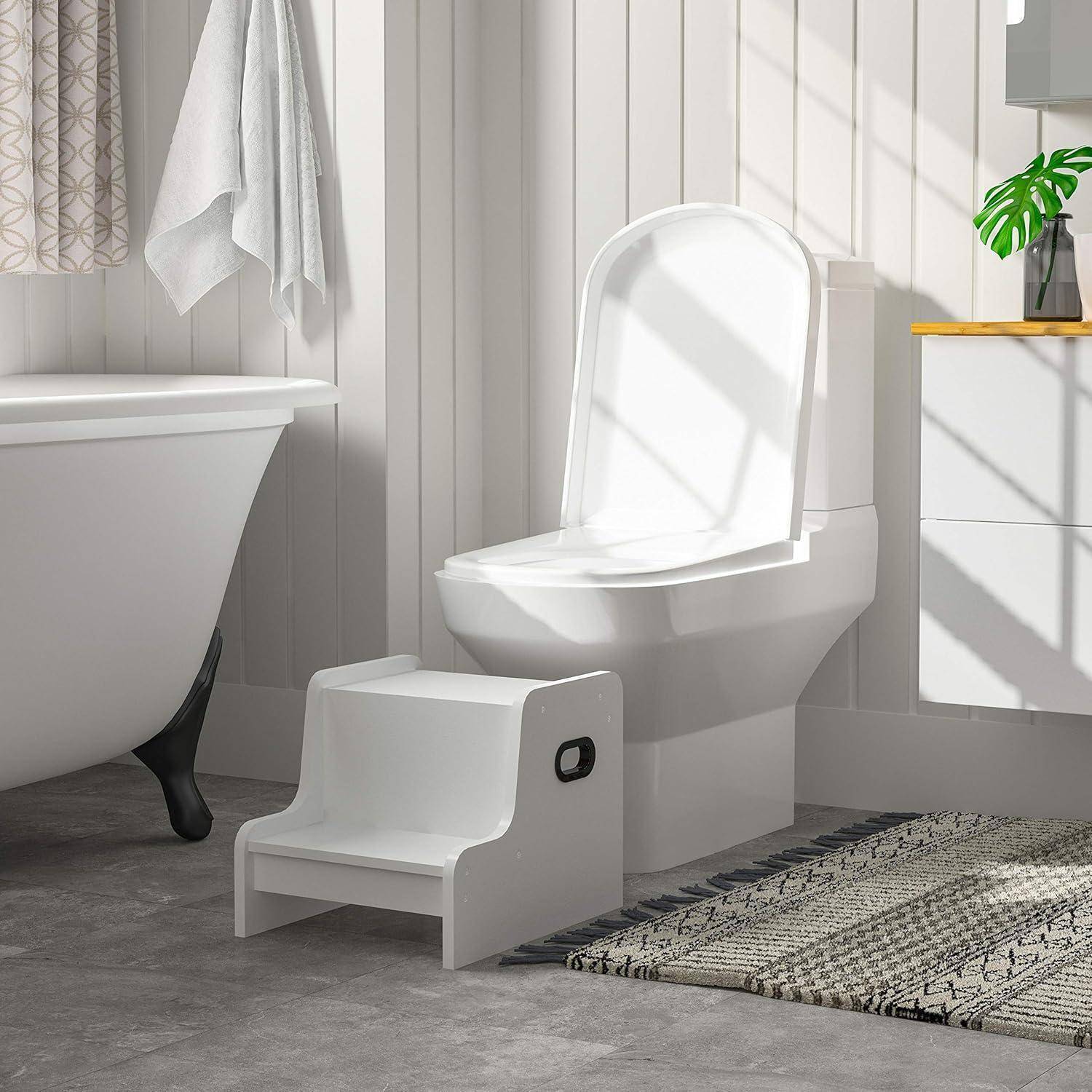 Ein gut beleuchtetes Badezimmer zeigt eine weiße Toilette mit einem Tritthocker für Kinder davor, eine große Badewanne und einen Holzschrank, wodurch ein gemütlicher und funktionaler Raum entsteht.