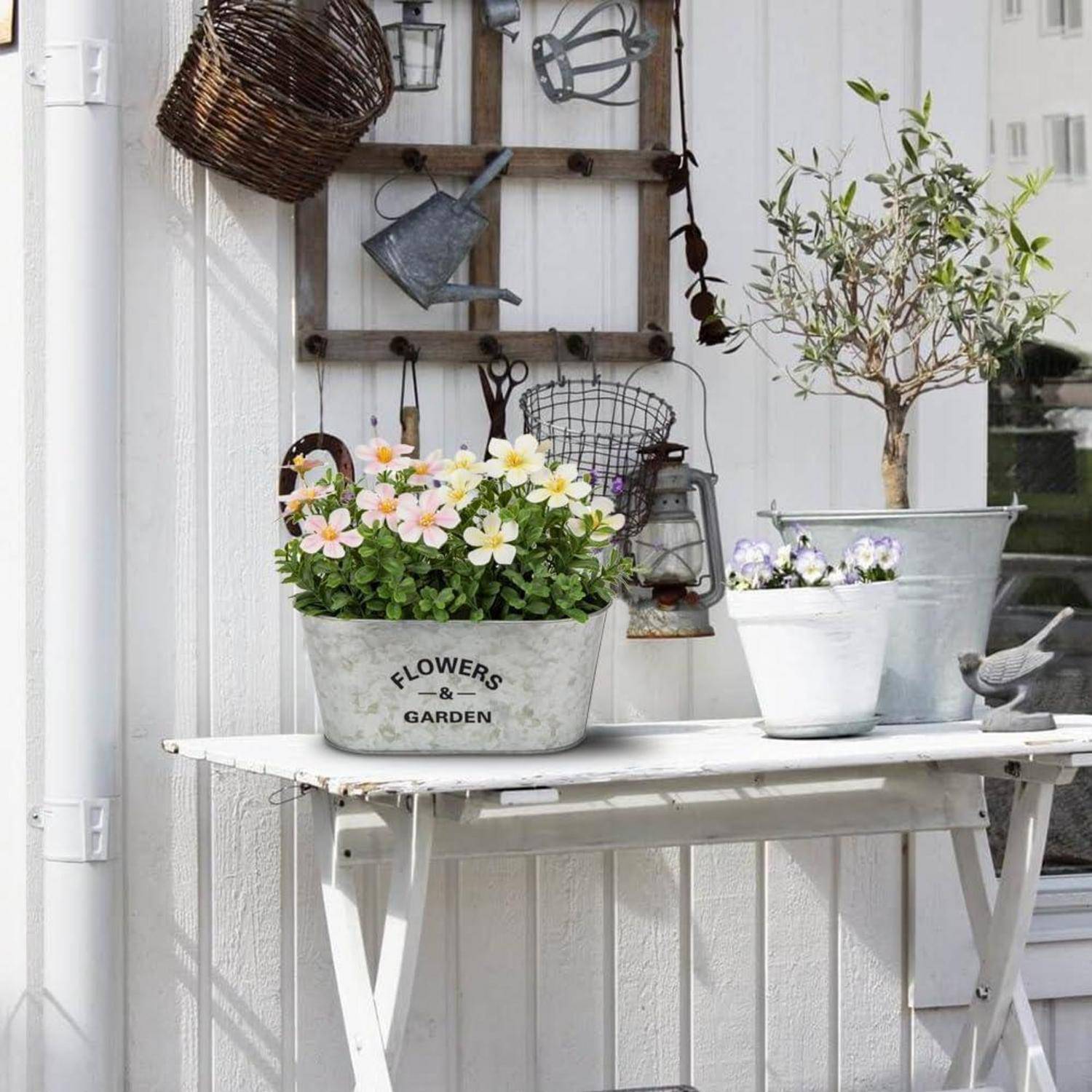 Ein weißer Gartentisch mit einem Topf mit rosa und weißen Blumen, beschriftet mit 
