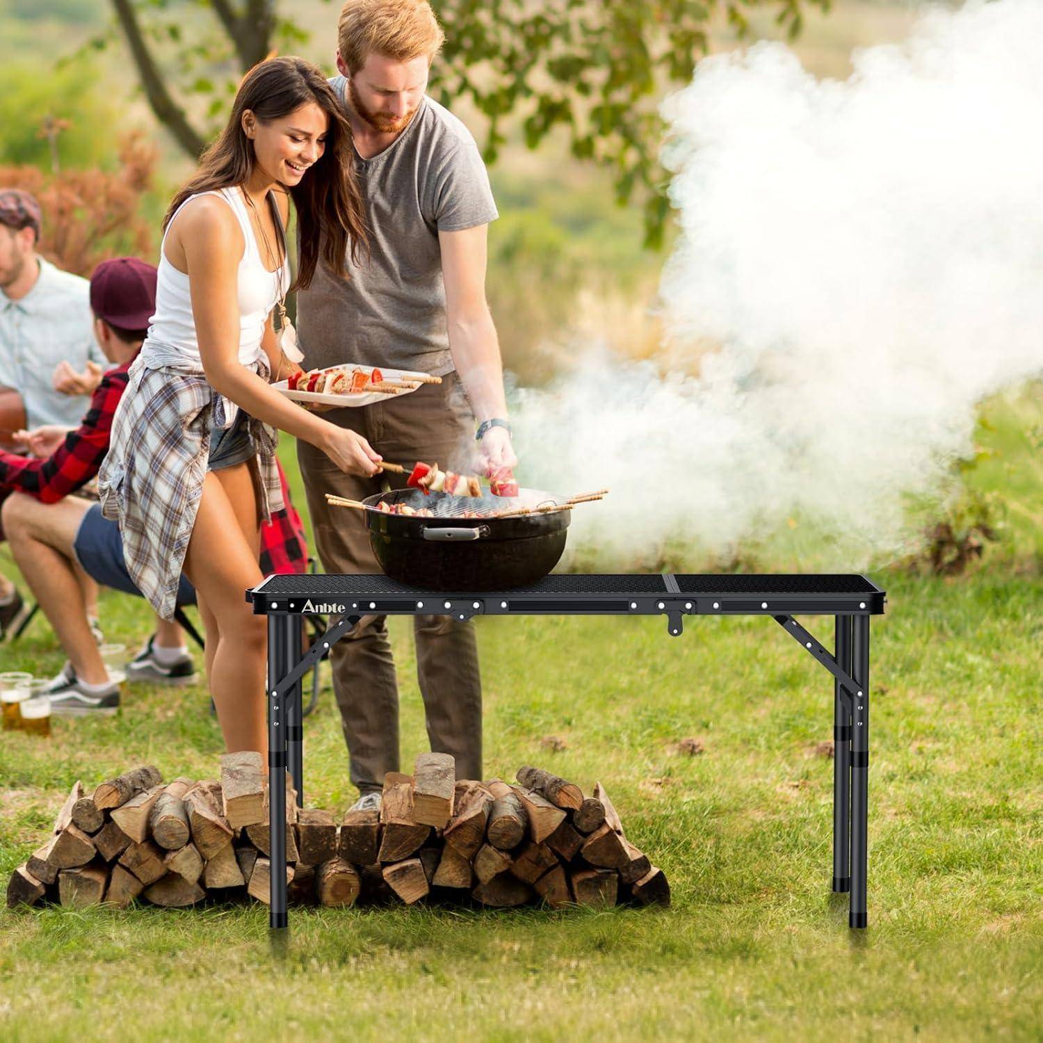Ein Paar, das Grillspieße auf einem Grill im Freien zubereitet, während im Hintergrund Freunde sitzen und die Zusammenkunft genießen.