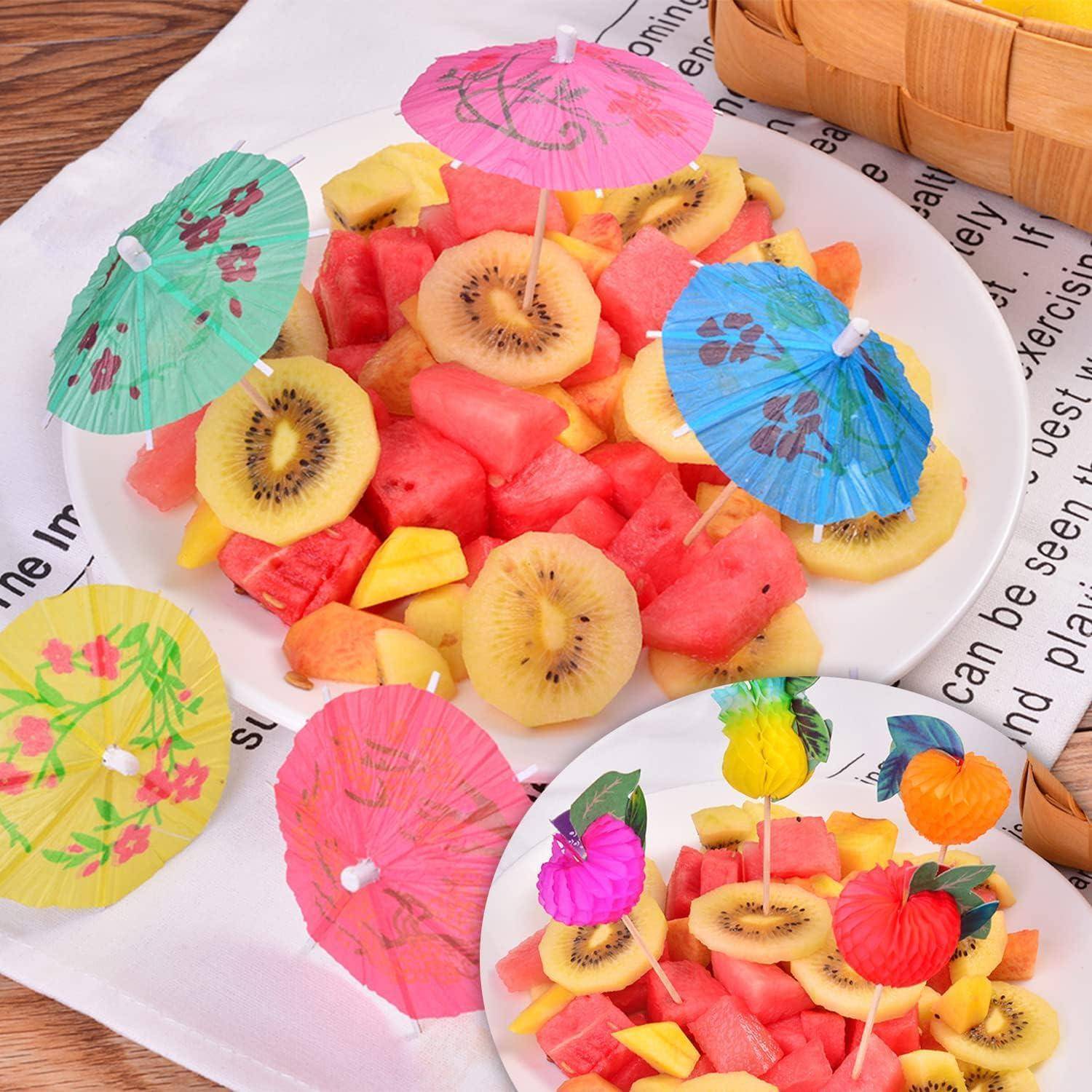 Eine Platte mit gemischtem Obst, darunter Wassermelone, Kiwi und Ananas, ist mit bunten Cocktail-Schirmen garniert, was eine tropische Präsentation ergibt.