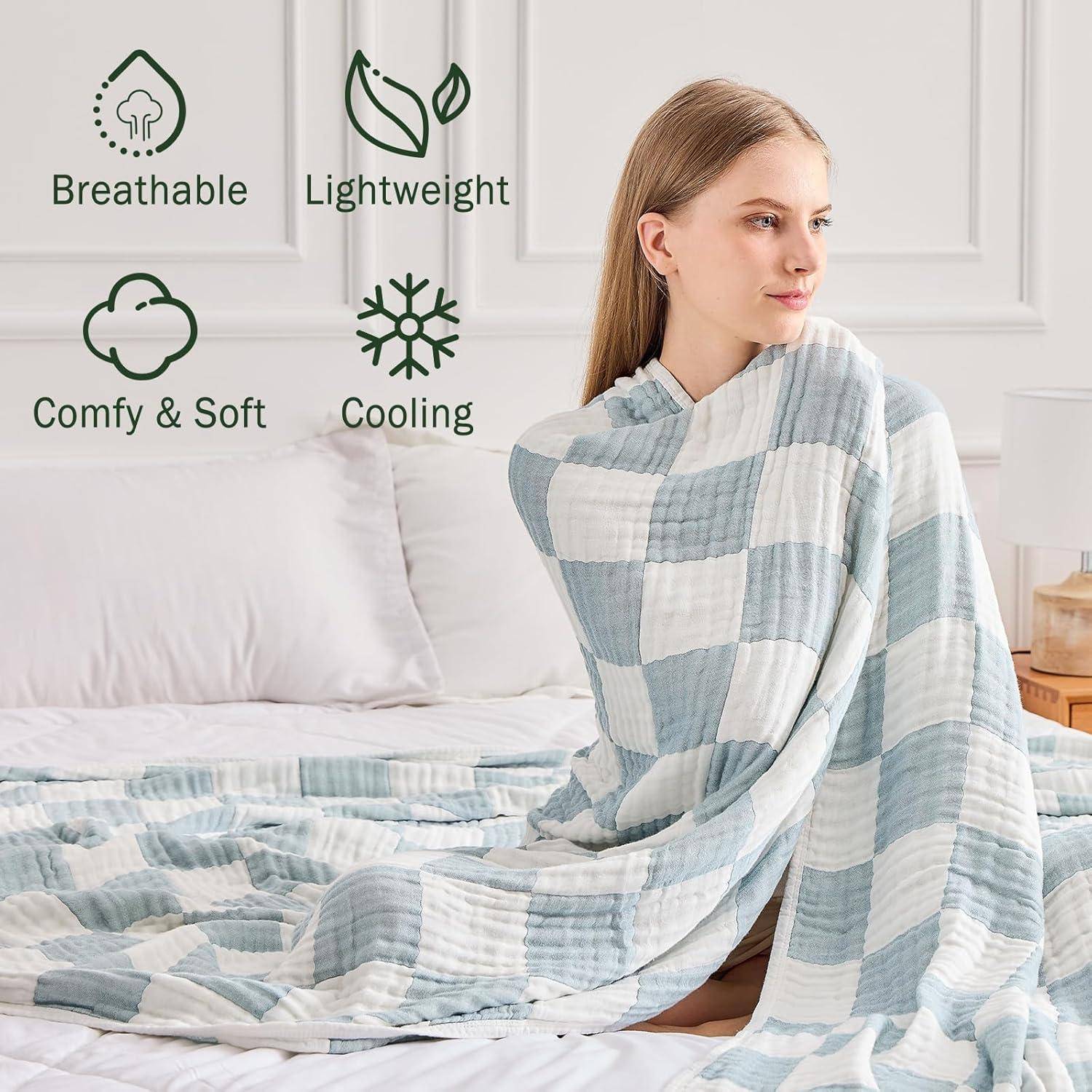 Eine Frau sitzt auf einem Bett, eingehüllt in eine blau-weiß karierte Decke. Icons zeigen, dass die Decke atmungsaktiv, leicht, gemütlich, weich und kühlend ist.