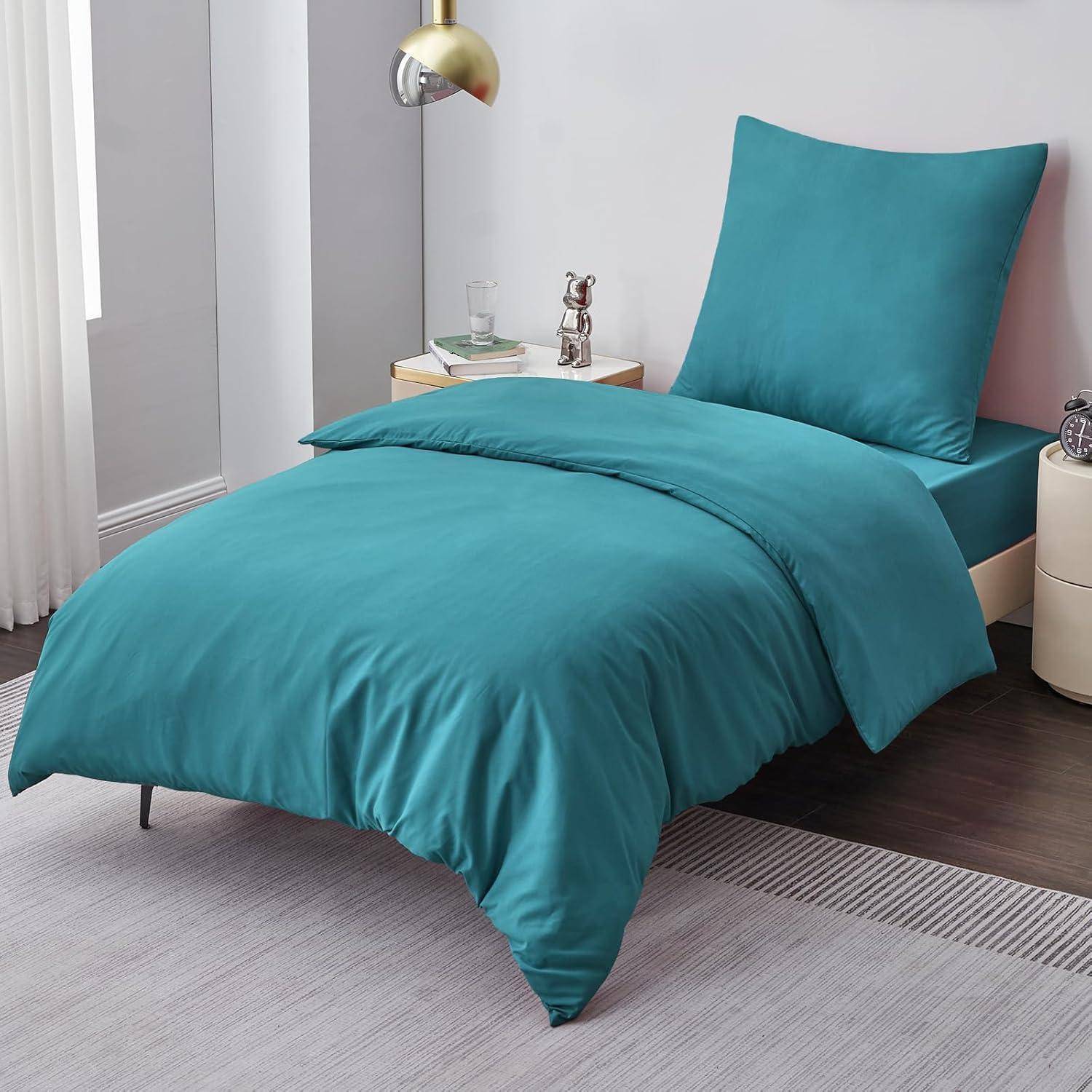 Ein ordentlich gemachtes Bett mit Entenblau-Bettwäsche, einschließlich Bettdecke und Kissen, neben einem kleinen Nachttisch mit einem Glas und einem Buch.