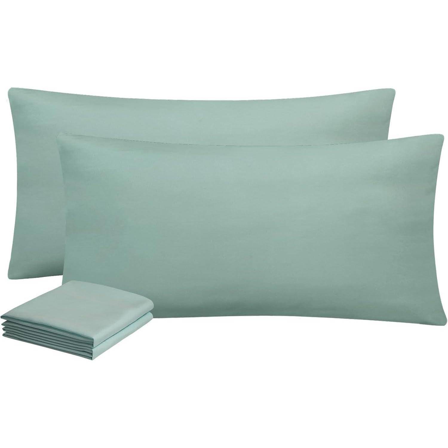 Zwei aquafarbene Kissenbezüge und gefaltete Laken, die eine weiche und glatte Stofftextur präsentieren, die sich perfekt für Bettwäsche eignet.