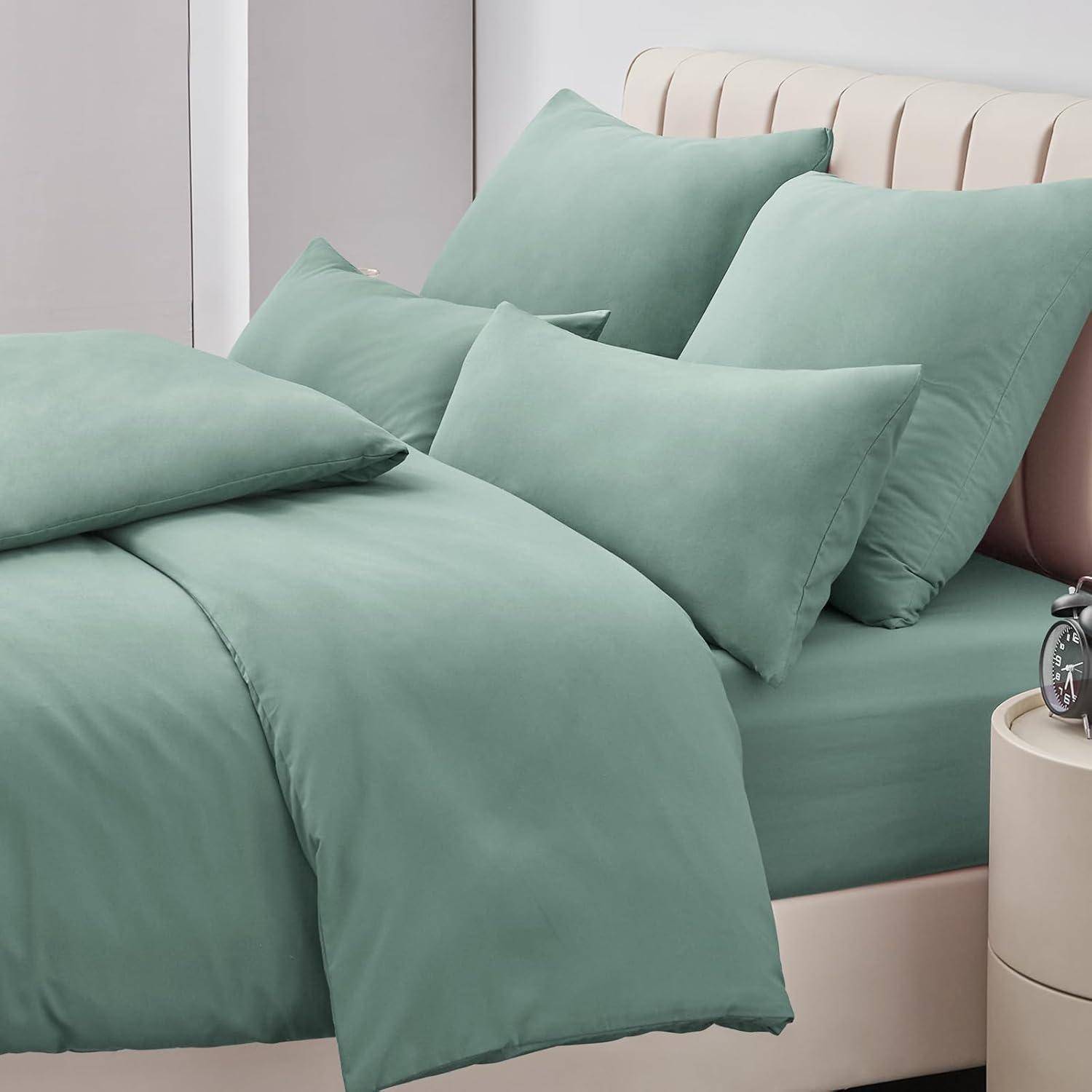 Ein ordentlich gemachtes Bett mit hellgrünen Bettwäsche, Kissen und Bettdecke, neben einem beigen gepolsterten Kopfteil und einem kleinen Nachttisch.