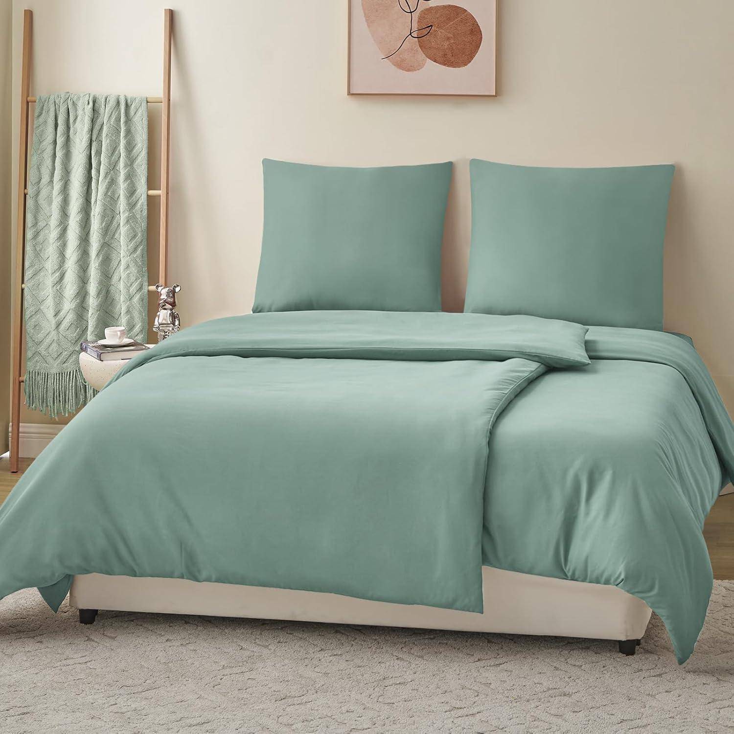 Ein ordentlich gemachtes Bett mit petrolfarbener Bettwäsche in einem sanft beleuchteten Schlafzimmer. Eine Holzleiter trägt eine grüne Decke, und ein minimalistisches Kunstwerk hängt darüber.