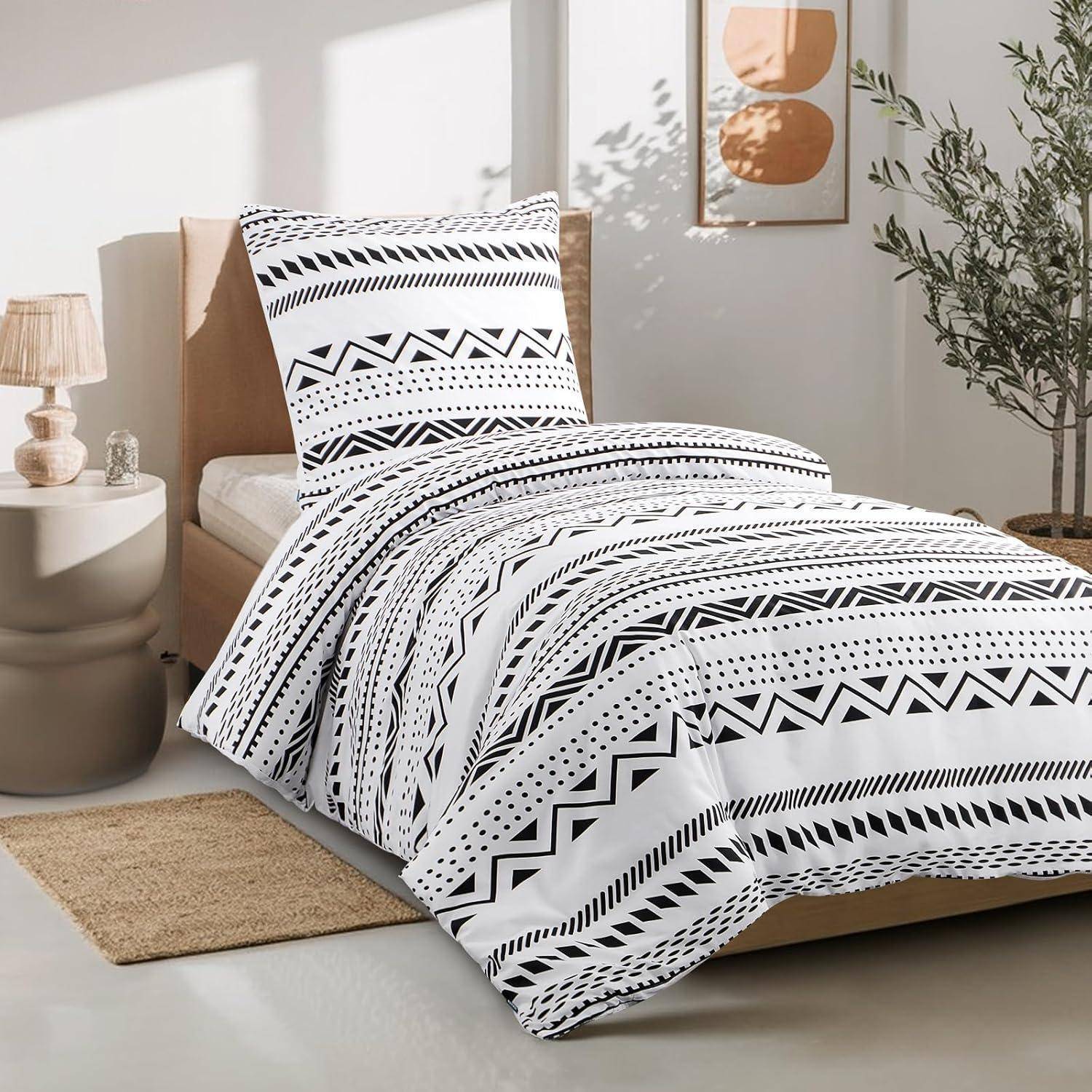 Ein ordentlich gemachtes Bett mit schwarzweißem geometrischem Bettwäschenmuster in einem gemütlichen Schlafzimmer. Eine Pflanze und eine kleine Lampe befinden sich auf beiden Seiten.