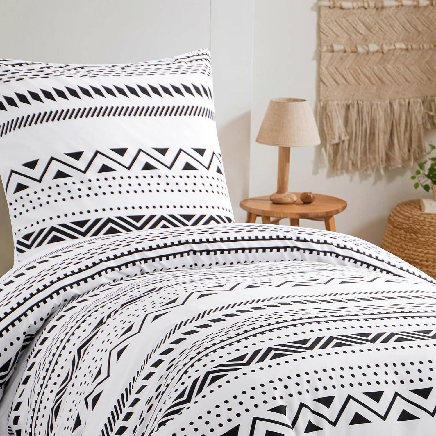 Geometrisches gemustertes Bettwäsche-Set mit schwarzen und weißen Zickzacks und Punkten. Ein Kissen und eine Decke auf einem Bett, mit einem Holz-Nachttisch in der Nähe.