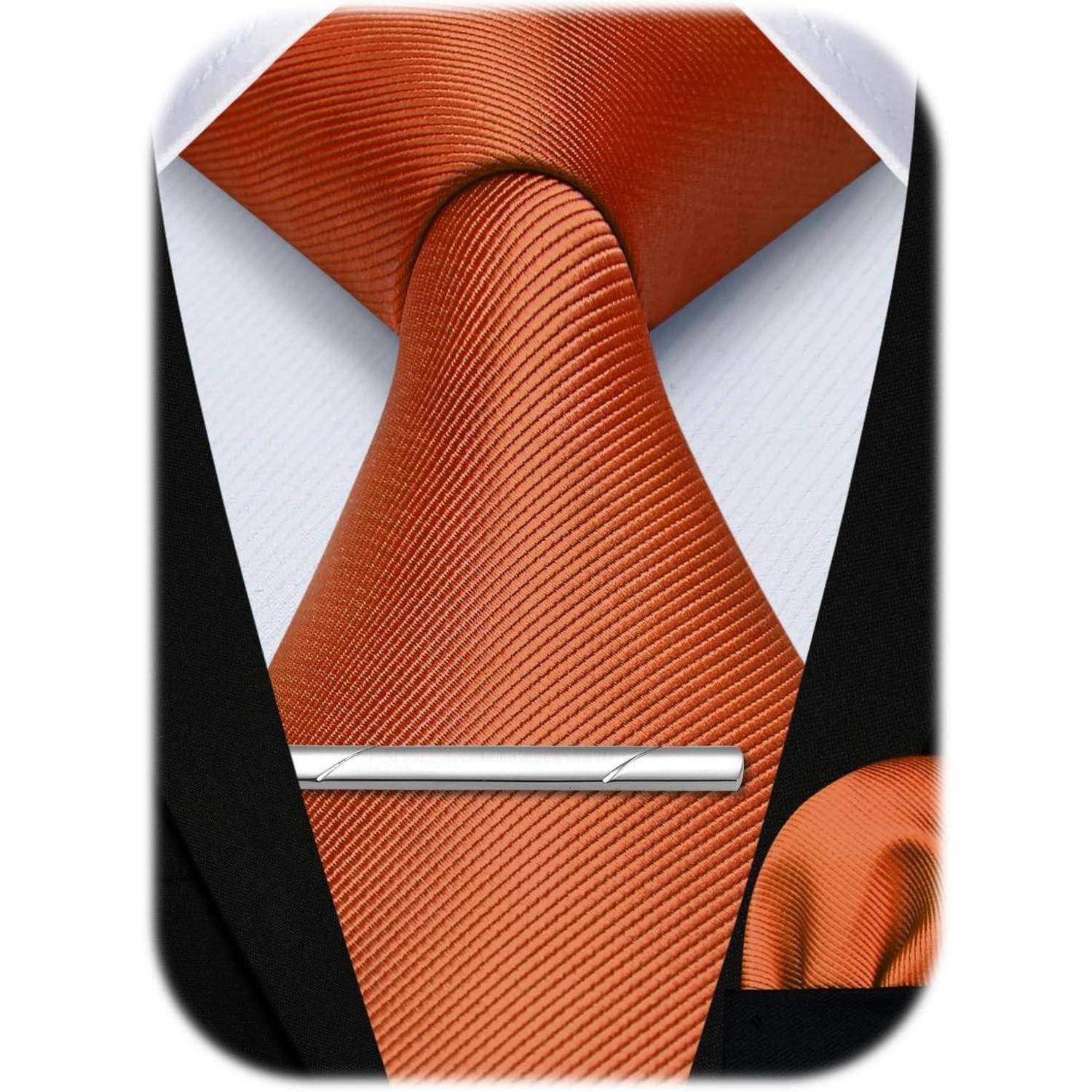 Eine orange Seidenkrawatte mit einer silbernen Krawattennadel ist ordentlich über einem weißen Hemd mit Kragen und einer schwarzen Anzugsjacke getragen.