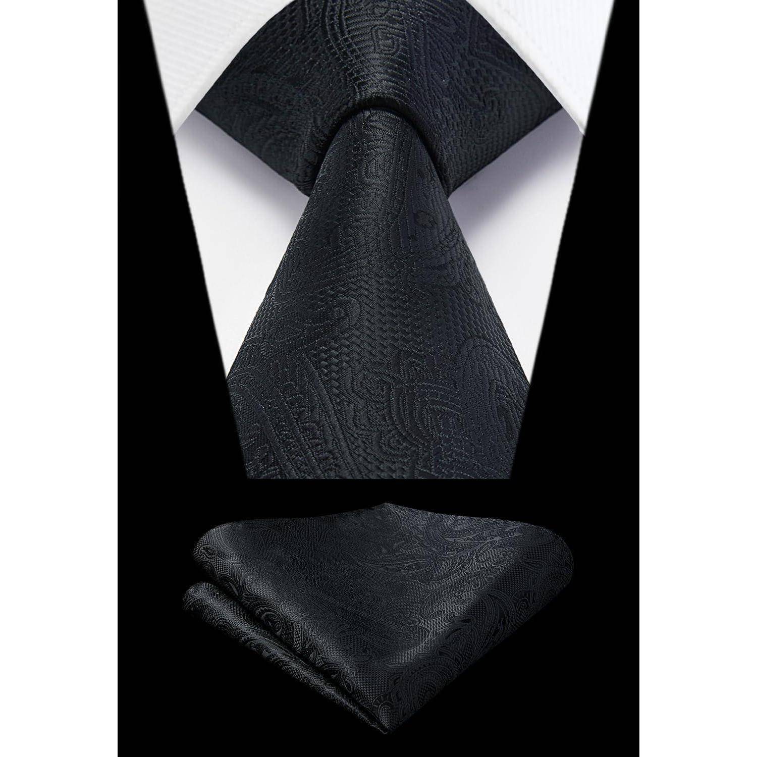 Eine schwarze Paisley-Krawatte wird vor einem weißen Hemd und einem schwarzen Anzug präsentiert, zusammen mit einem passenden Einstecktuch.