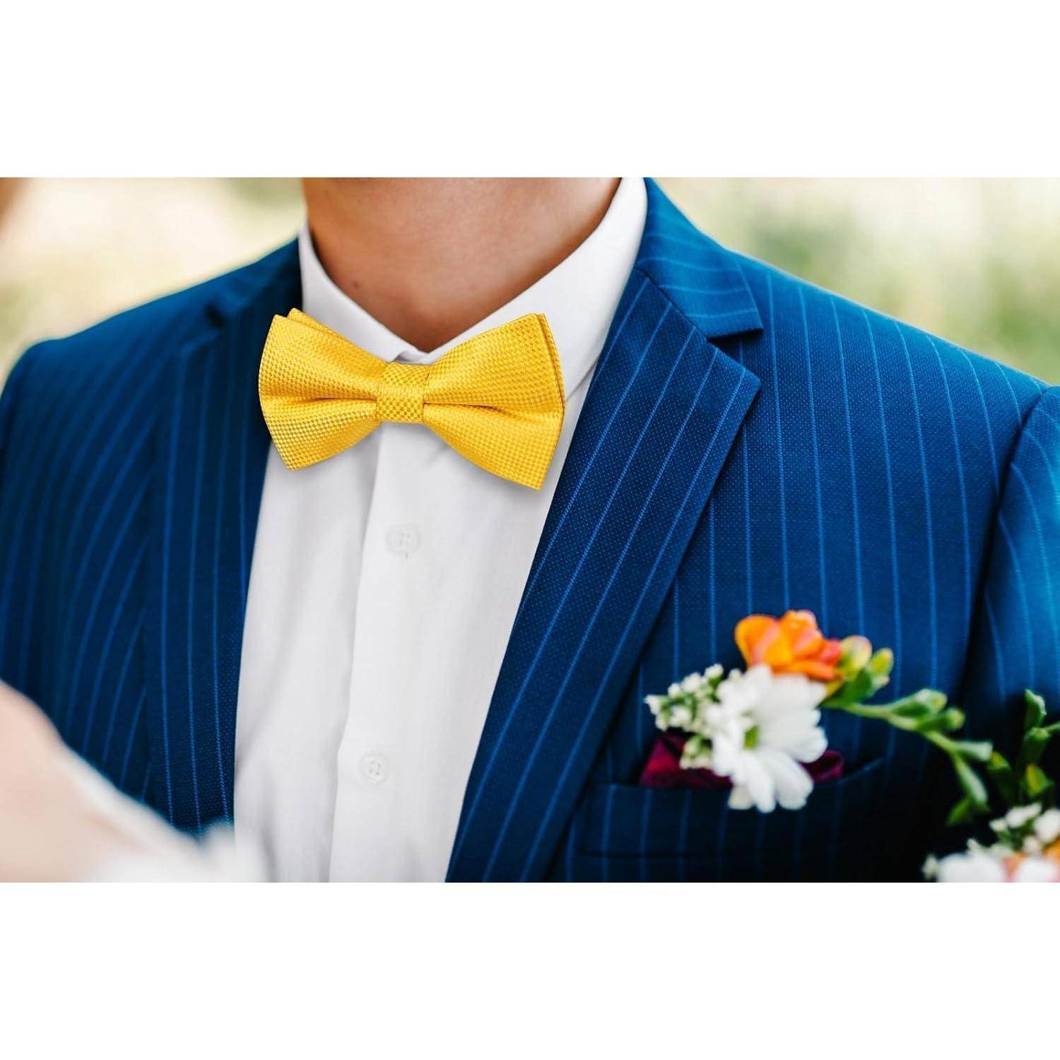 Eine Person in einem blauen Nadelstreifenanzug mit einer gelben Fliege und einem farbenfrohen Einstecktuch hält einen kleinen Blumenstrauß.