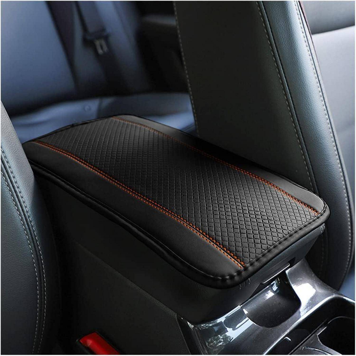 Innenraum eines Autos mit einer schwarzen Lederarmlehne, die mit orangefarbenen Nähten zwischen zwei Sitzen versehen ist und deren Design und Handwerkskunst hervorhebt.