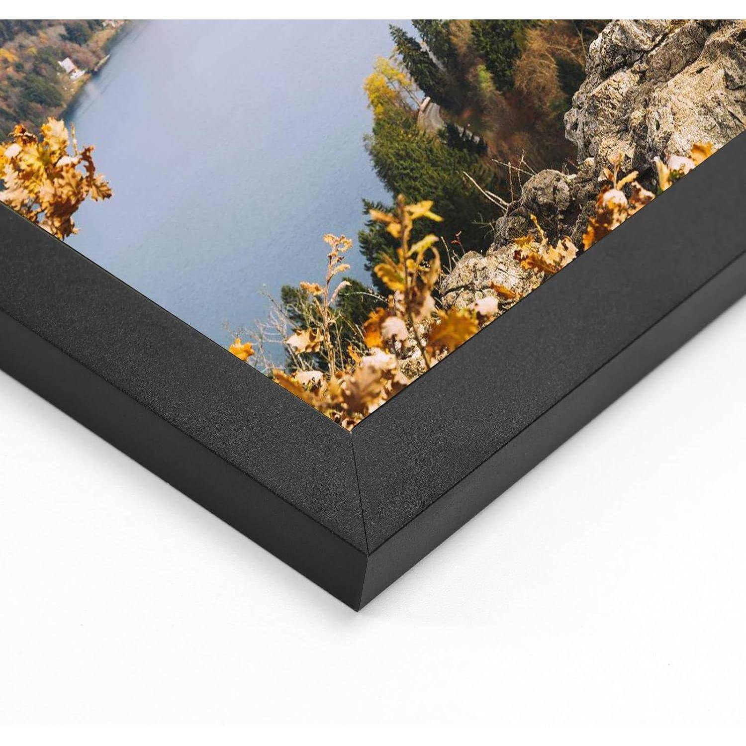 Ein schwarzgerahmtes Foto zeigt einen ruhigen See, umgeben von Herbstbäumen, aufgenommen von einer felsigen Klippe aus.