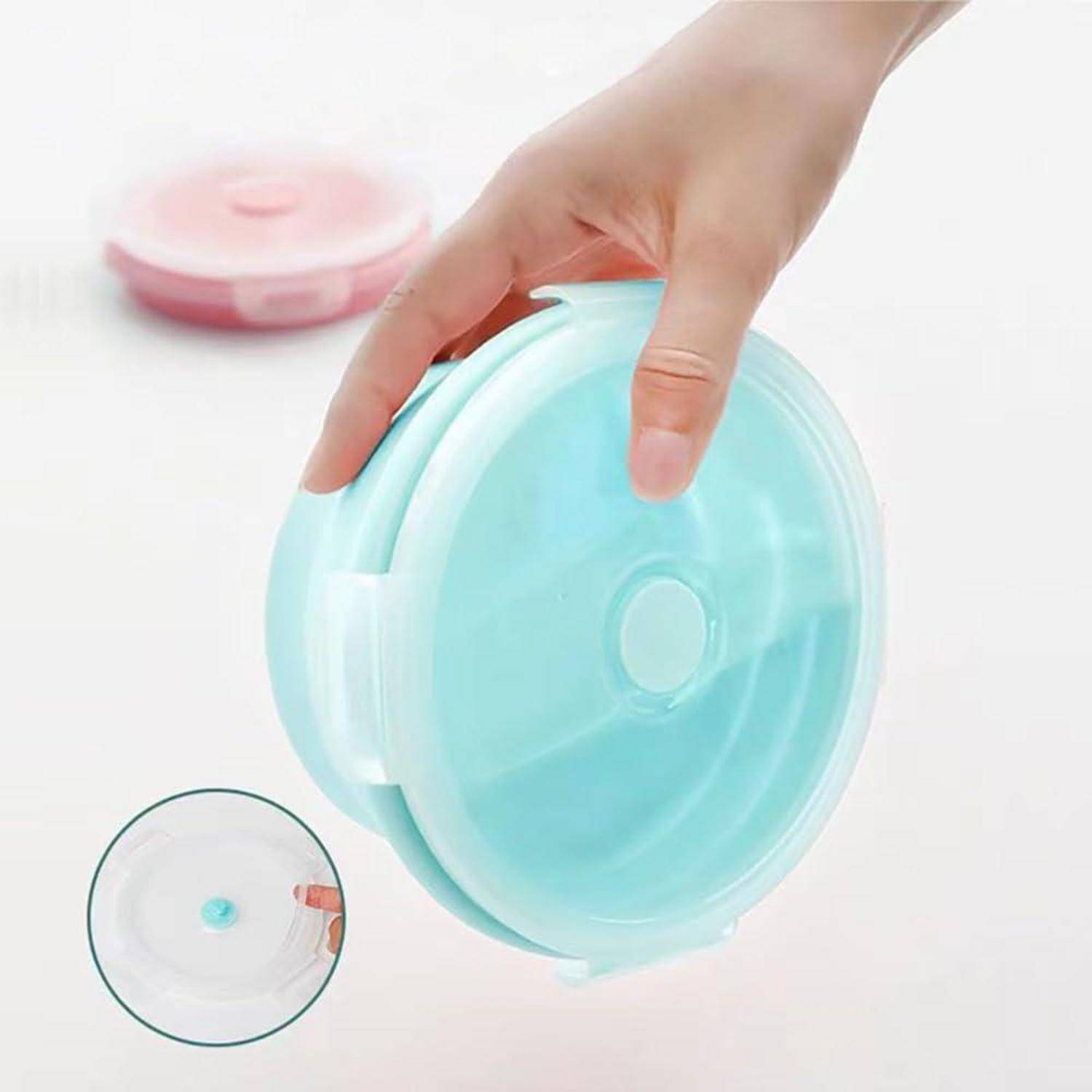 Eine Hand hält einen runden, blauen luftdichten Behälter mit einem transparenten Deckel. Ein ähnlicher roter Behälter ist im Hintergrund unscharf.