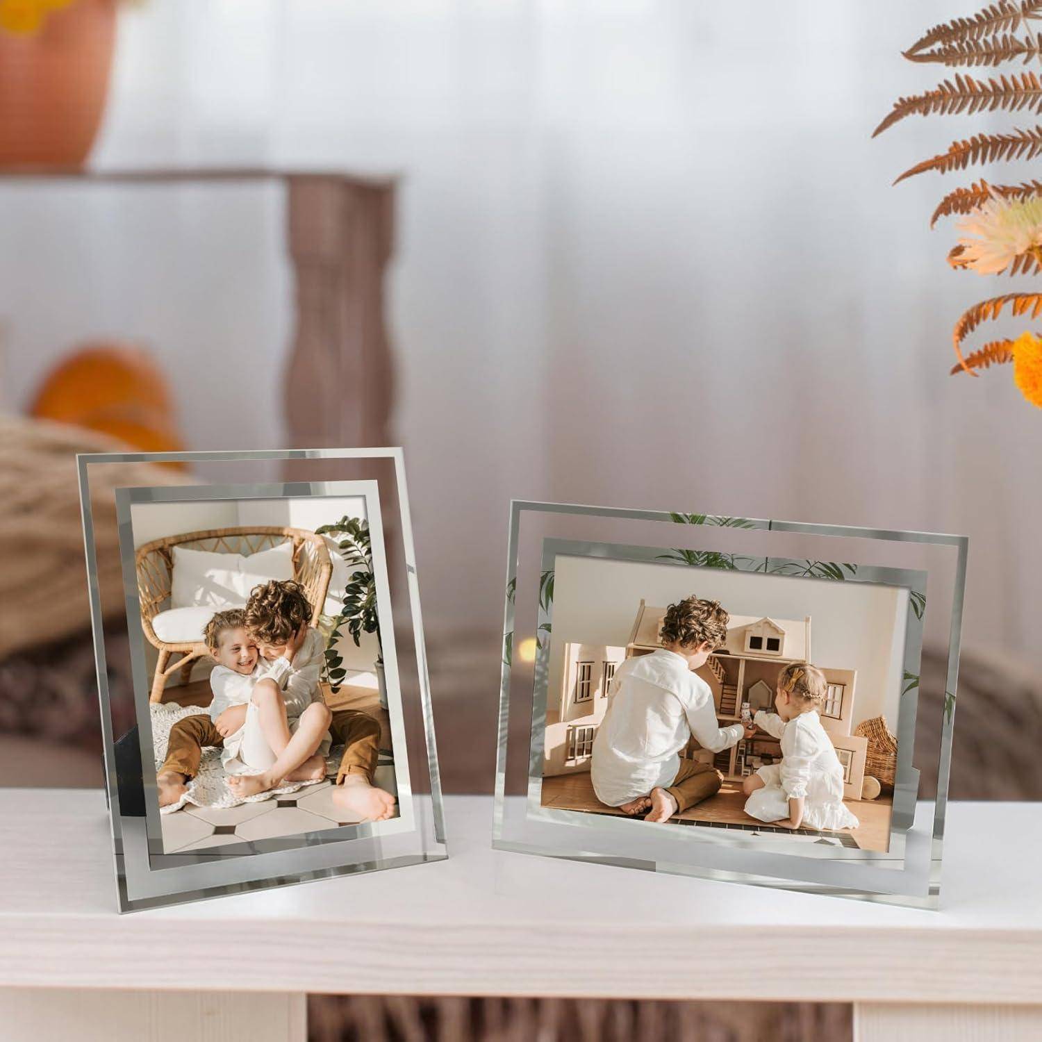 Zwei Glasfotorahmen auf einem Tisch, die jeweils Bilder von einem Elternteil und Kind zeigen, die gemeinsam in Innenräumen spielen. Der Hintergrund enthält dezente Dekorationselemente.