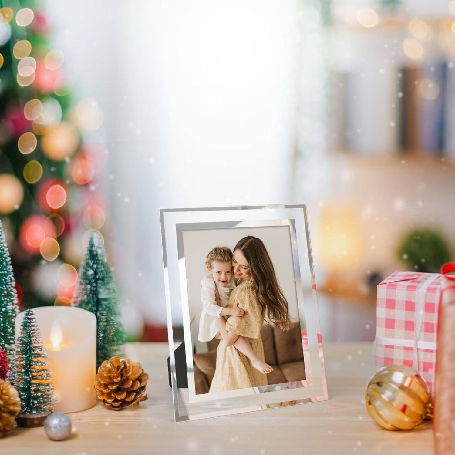 Ein gerahmtes Foto von zwei lächelnden Kindern steht auf einem Tisch, der mit Weihnachtsschmuck dekoriert ist und mit einem unscharfen Weihnachtsbaum im Hintergrund versehen ist.