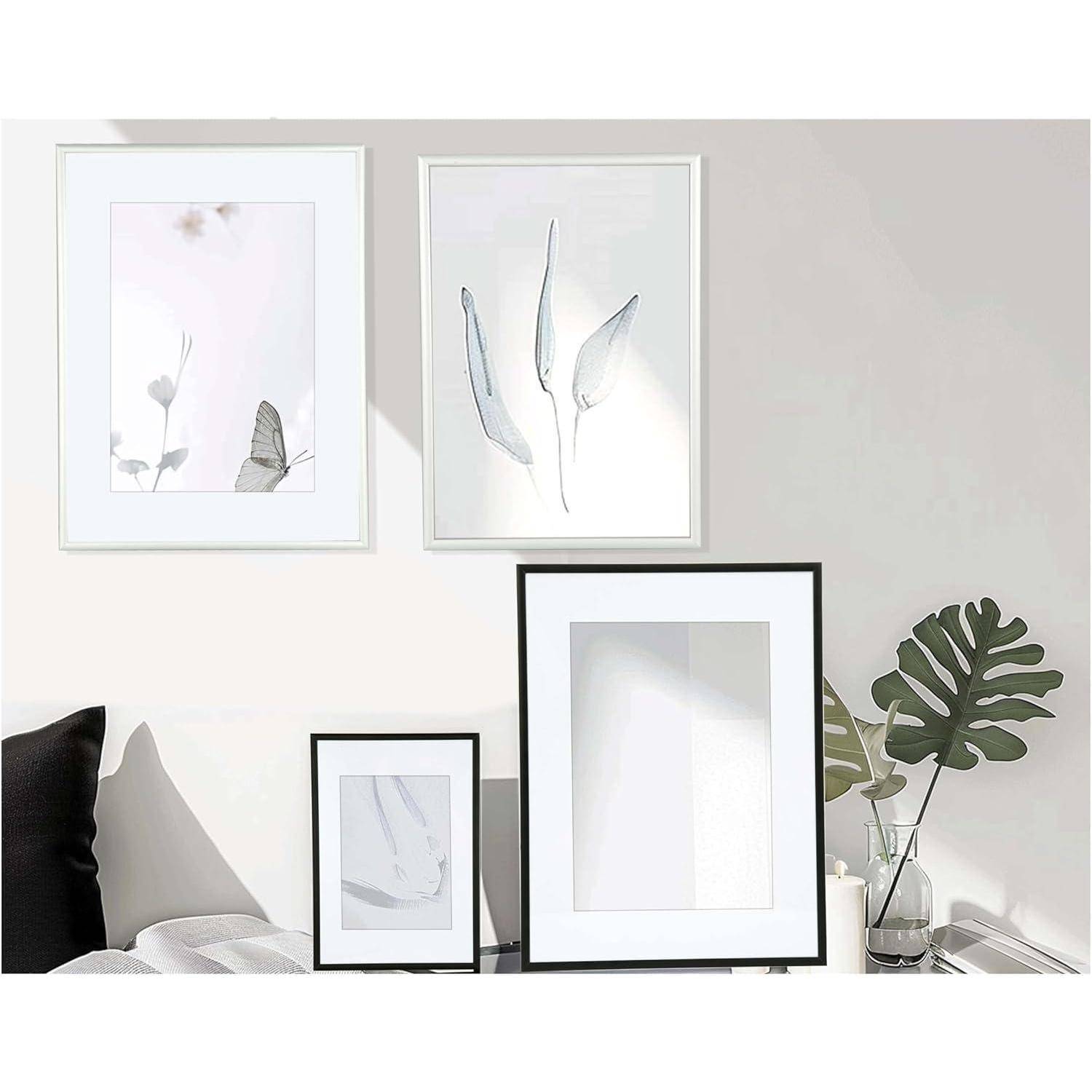 Ein moderner Wohnzimmerbereich zeigt minimalistische Kunstdrucke mit Naturmotiven in weißen Rahmen. Eine Couch und eine belaubte Pflanze befinden sich in der Nähe.