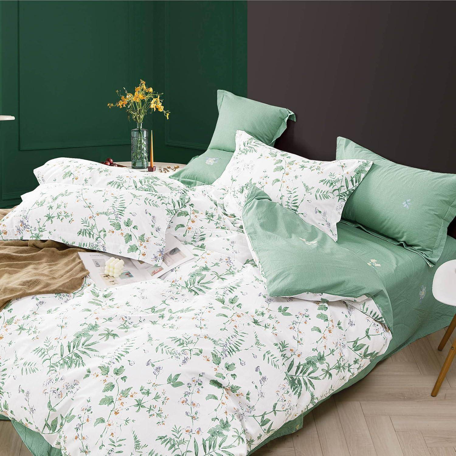 Ein Bett mit grün-weißer Blumenbettwäsche, grünen Kissen und einem Holzstuhl daneben. Eine Vase mit Blumen steht auf dem Nachttisch.