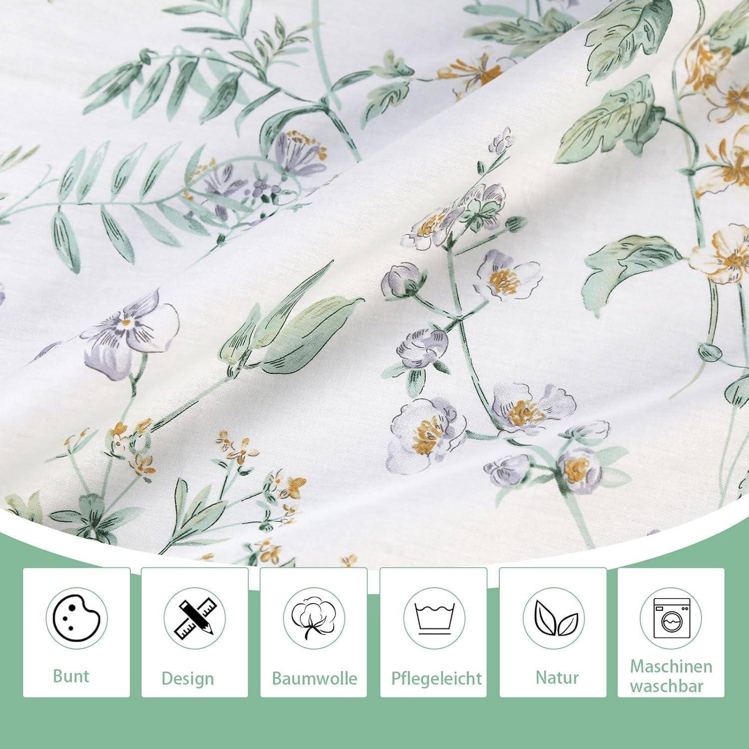 Blumengemusterte Stoffe mit grünen Blättern und weißen Blüten. Symbole darunter zeigen Eigenschaften: farbenfroh, Baumwolle, pflegeleicht, natürlich, maschinell waschbar.