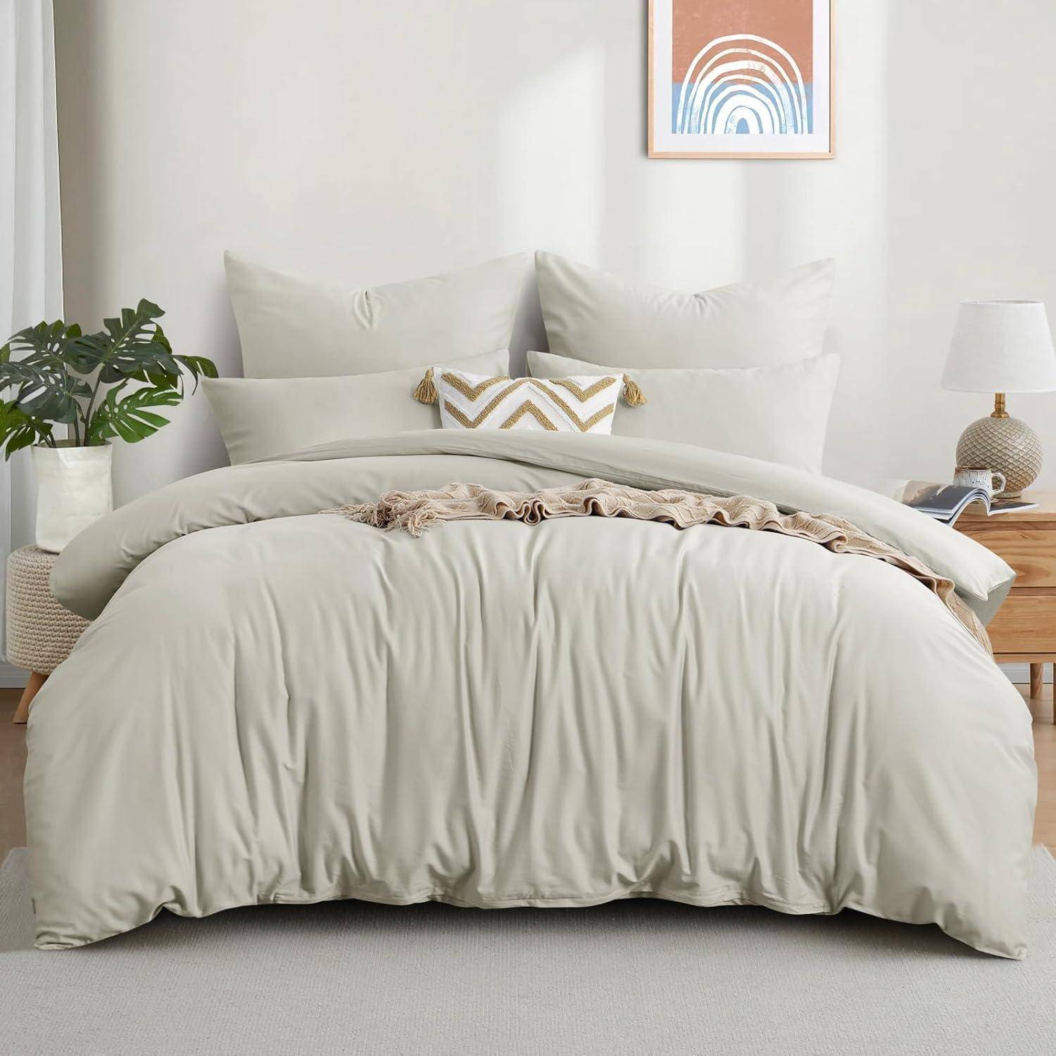 Ein ordentlich gemachtes Bett mit beigen Bettwäsche, dekorativen Kissen und einem Zickzack-gemusterten Kissen. Auf beiden Seiten stehen eine Pflanze und eine Lampe. Über dem Bett hängt ein gerahmtes abstraktes Kunstwerk.