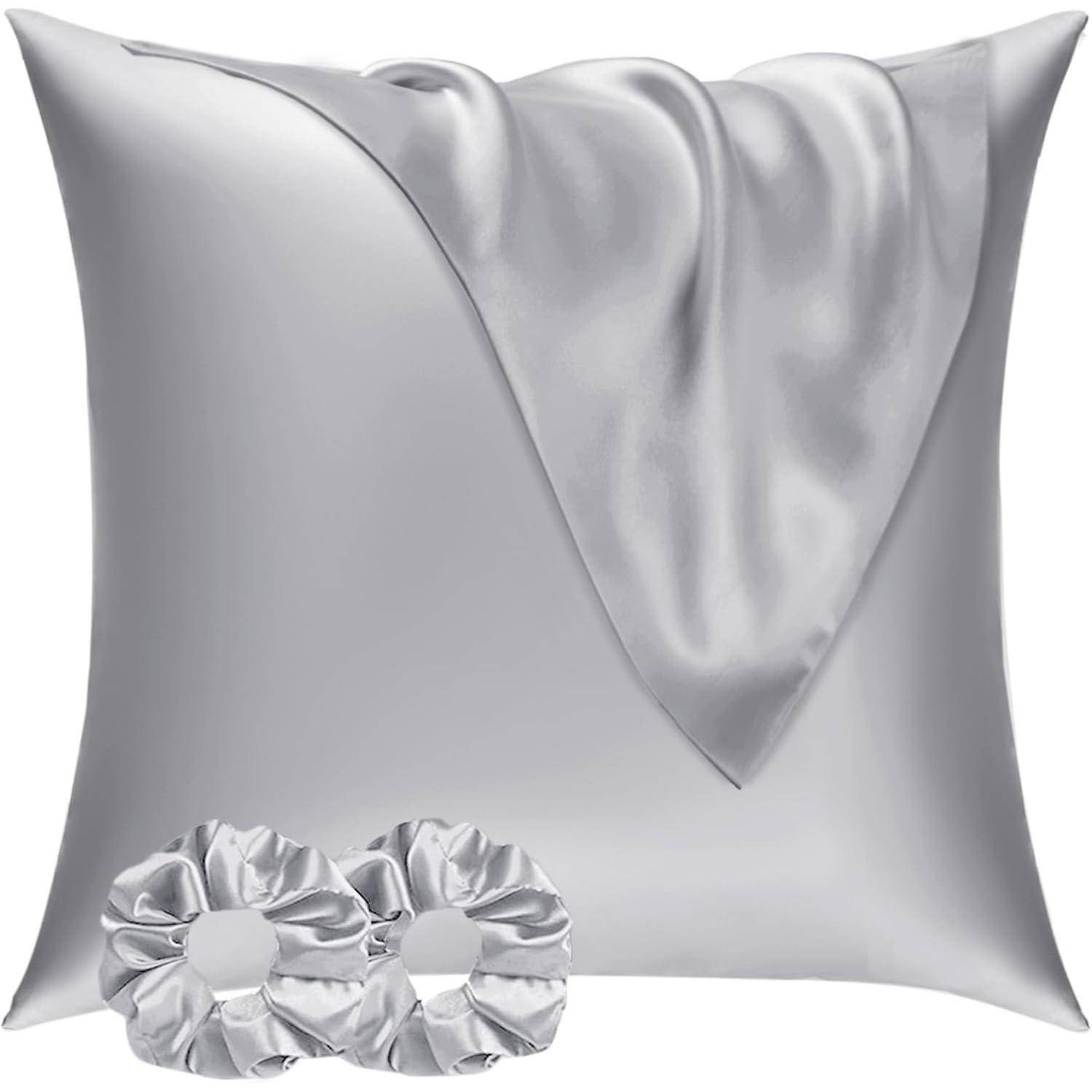 Ein silberfarbener Satin-Kissenbezug mit drapiertem Stoff oben, begleitet von zwei passenden Satin-Haargummis im Vordergrund.