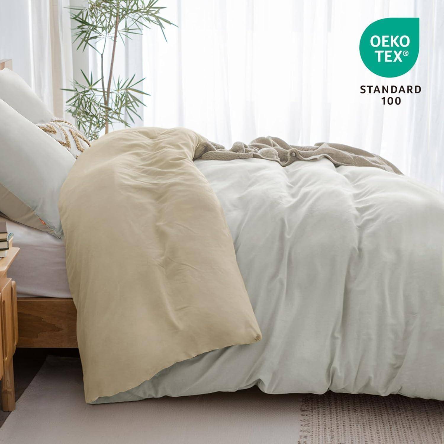 Ein ordentlich gemachtes Bett mit beige und weißer Bettwäsche, ein Nachttisch links und eine Pflanze im Hintergrund. Das Label 
