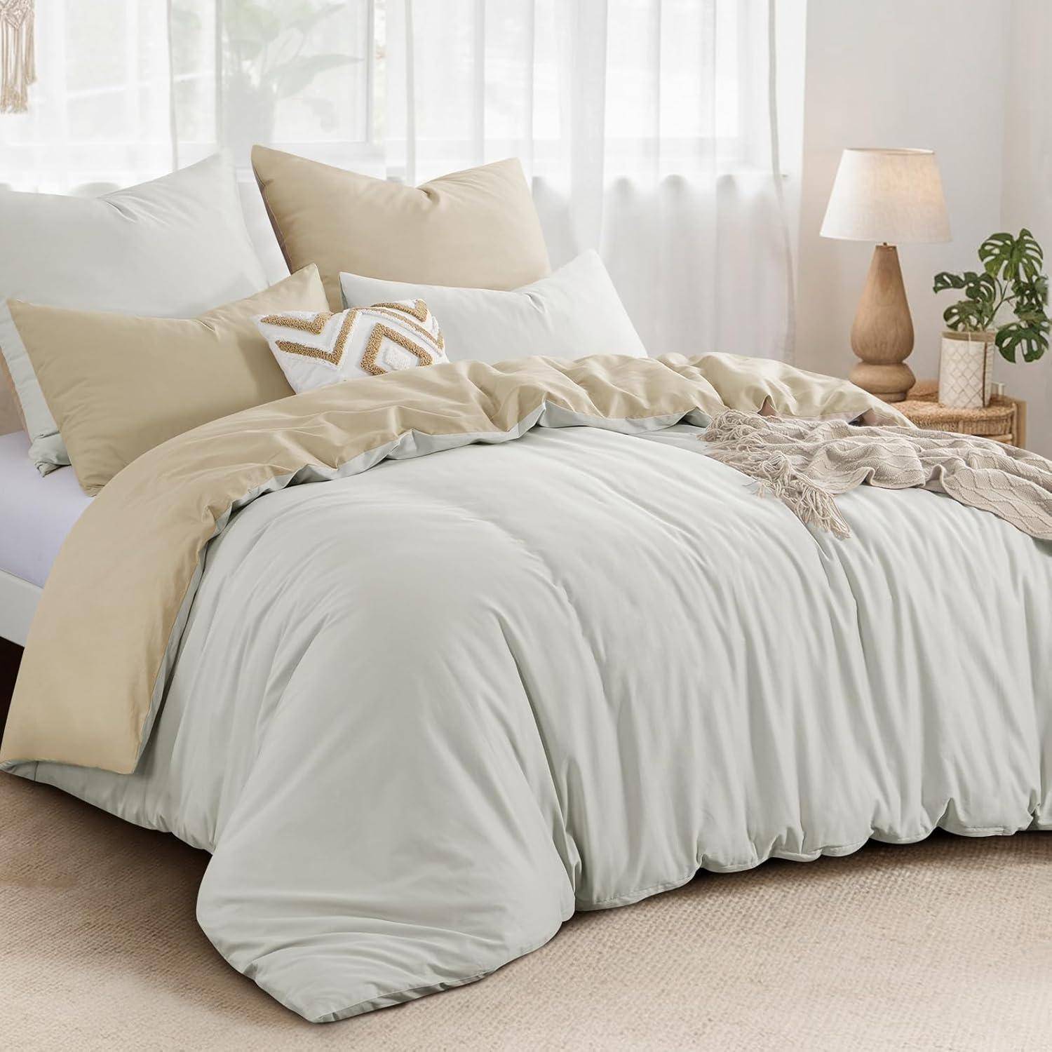Ein ordentlich gemachtes Bett mit weißer und beige-farbener Bettwäsche, ein Holznachttisch mit einer Lampe und einer Pflanze, in einem sanft beleuchteten Schlafzimmer.