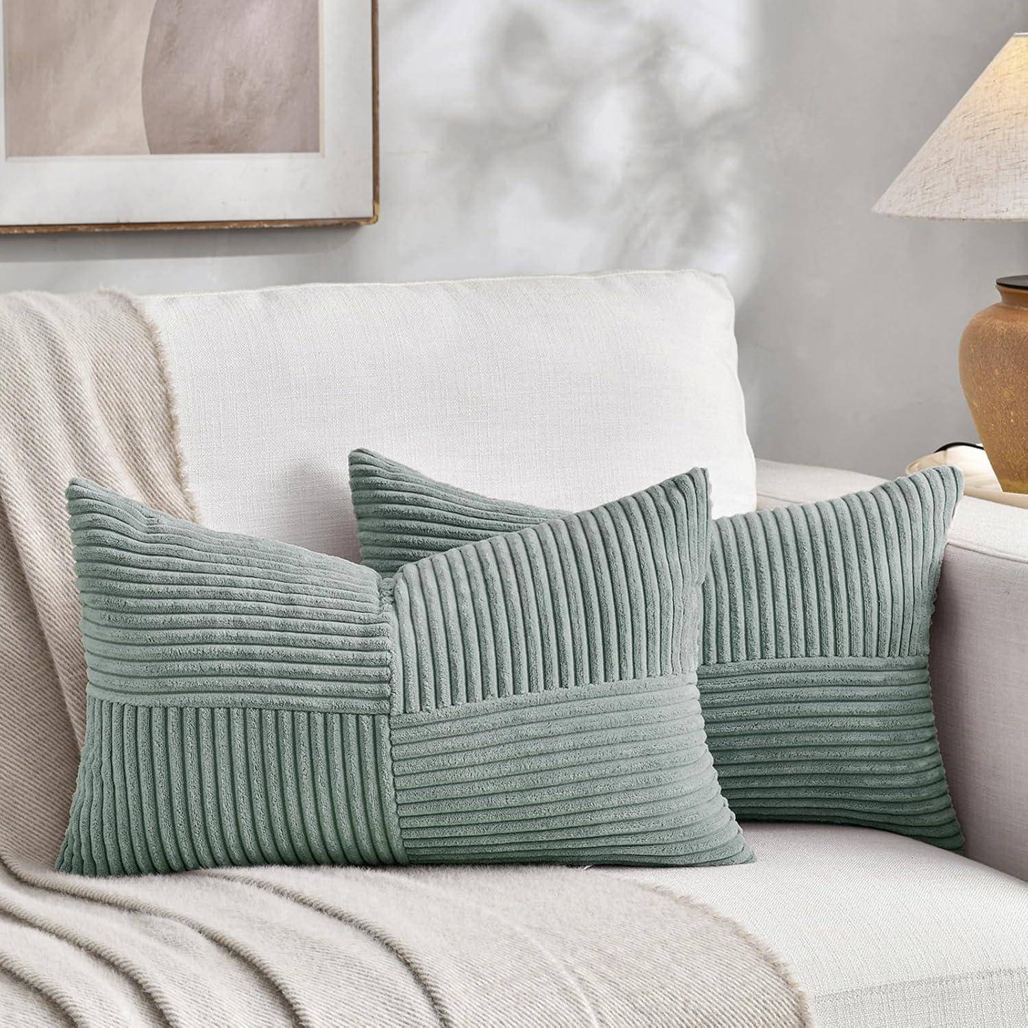 Ein weißes Sofa mit zwei strukturierten, grünen Kissen und einer beigen Decke in einer gemütlichen, hell beleuchteten Wohnzimmeratmosphäre.