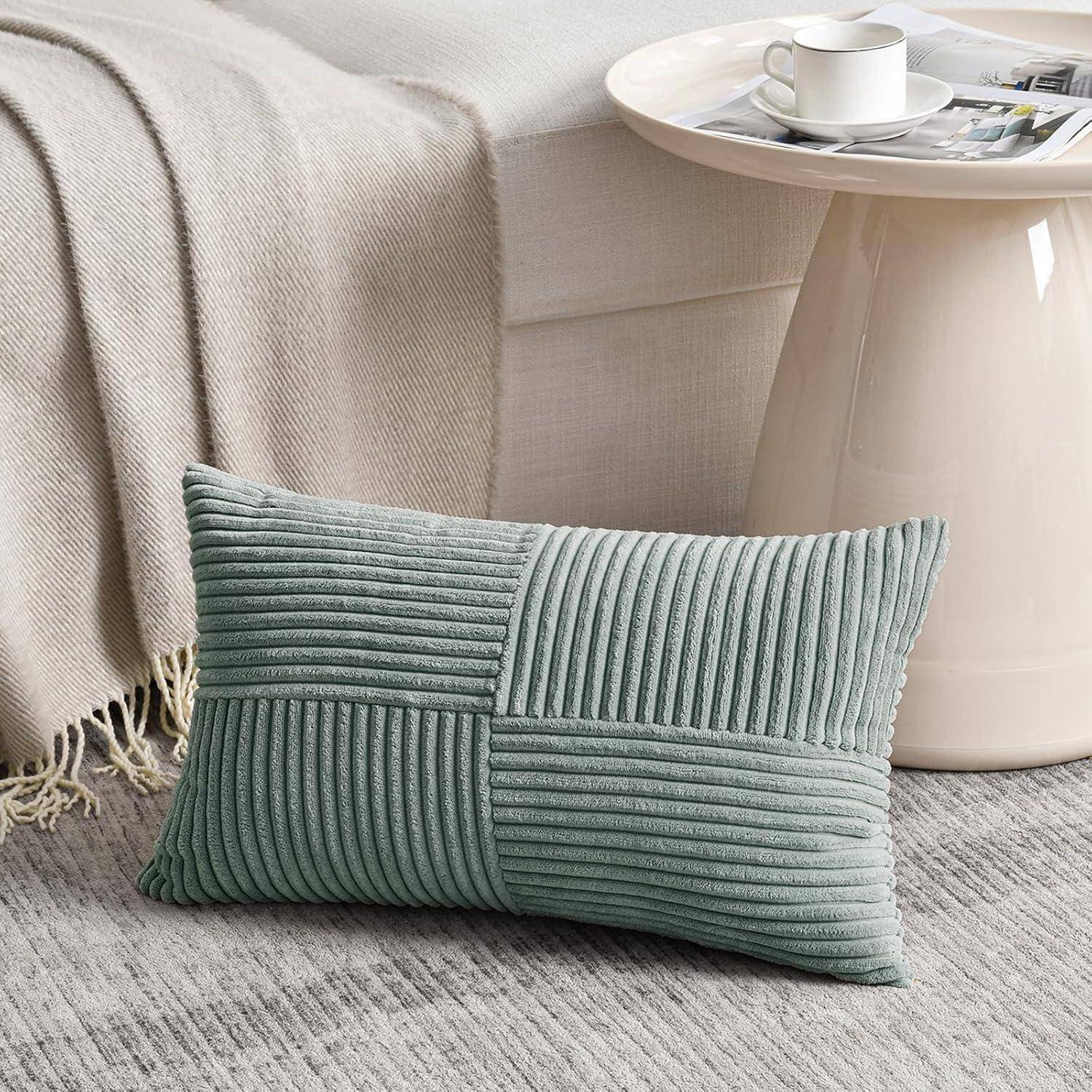 Hellgrünes strukturiertes Zierkissen auf einem beigen Teppich neben einem kleinen Couchtisch, auf dem eine weiße Tasse mit Untertasse neben einem grauen Sofa steht.