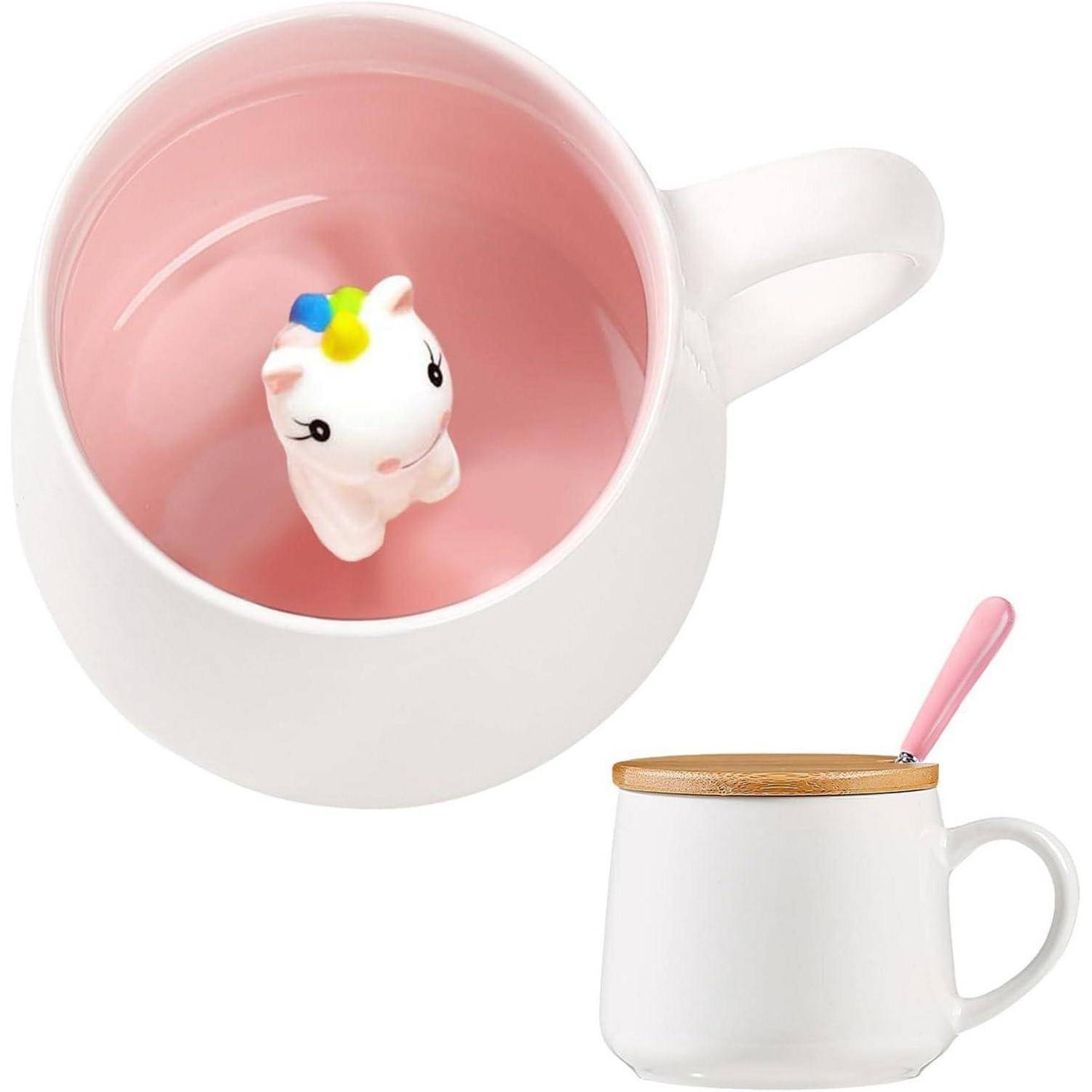Eine weiße Tasse mit einem Holzdeckel und rosa Innenseite offenbart eine Einhorn-Figur am Boden. Ein rosa Löffel liegt neben der Tasse.